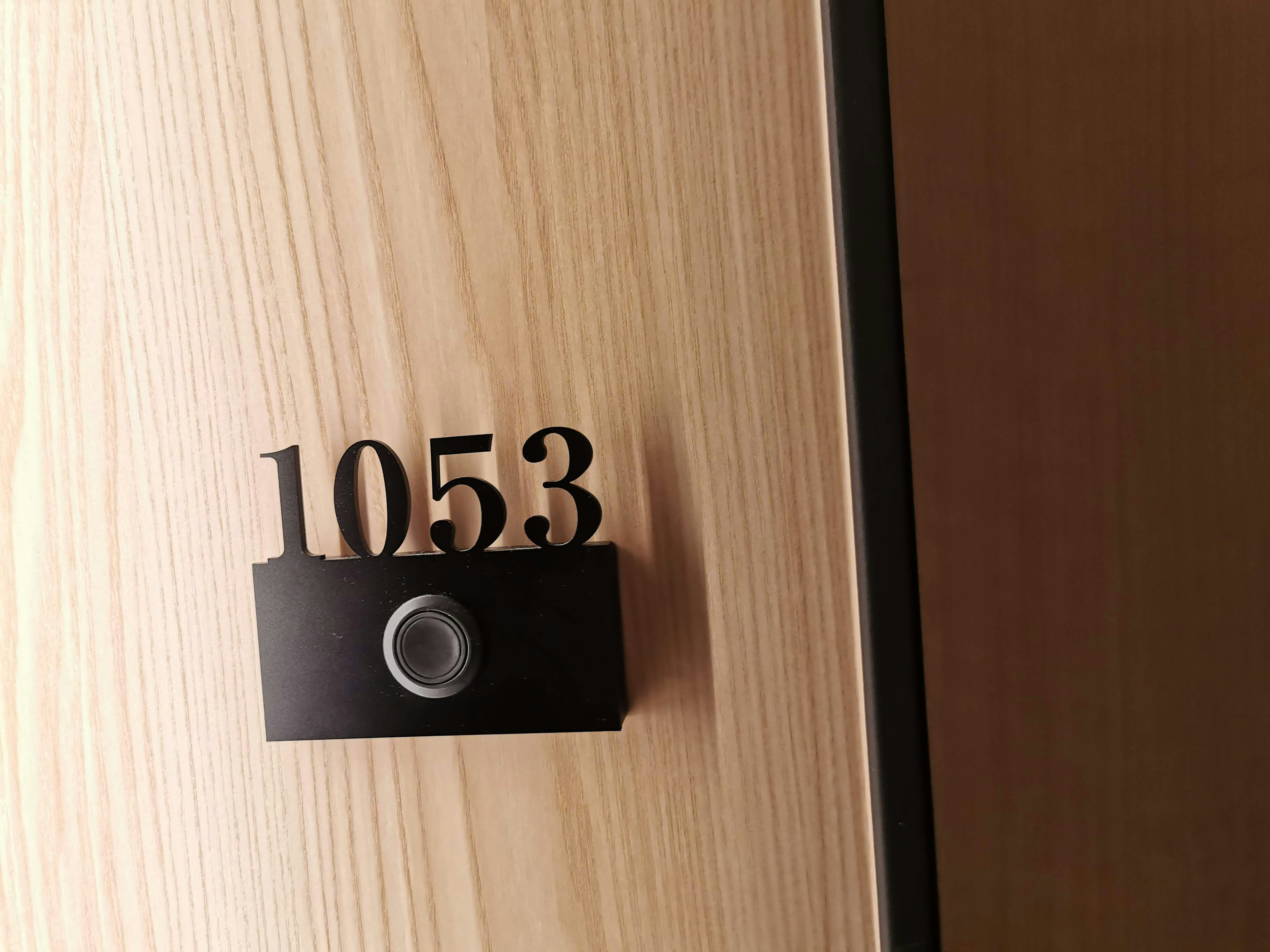 Biển số phòng “1053” gắn trên tường gỗ