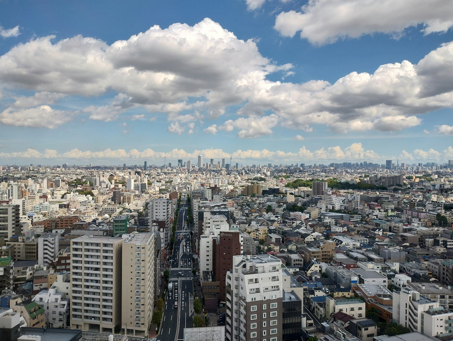 Un vasto paesaggio urbano di Tokyo sotto un cielo blu con nuvole