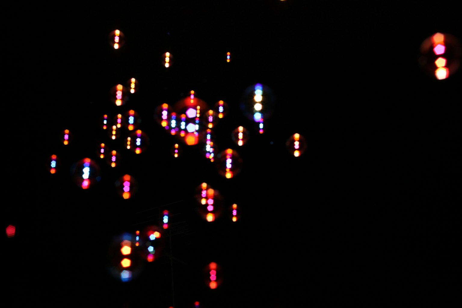 Bild mit bunten Lichtpunkten, die sich vor einem dunklen Hintergrund verteilen