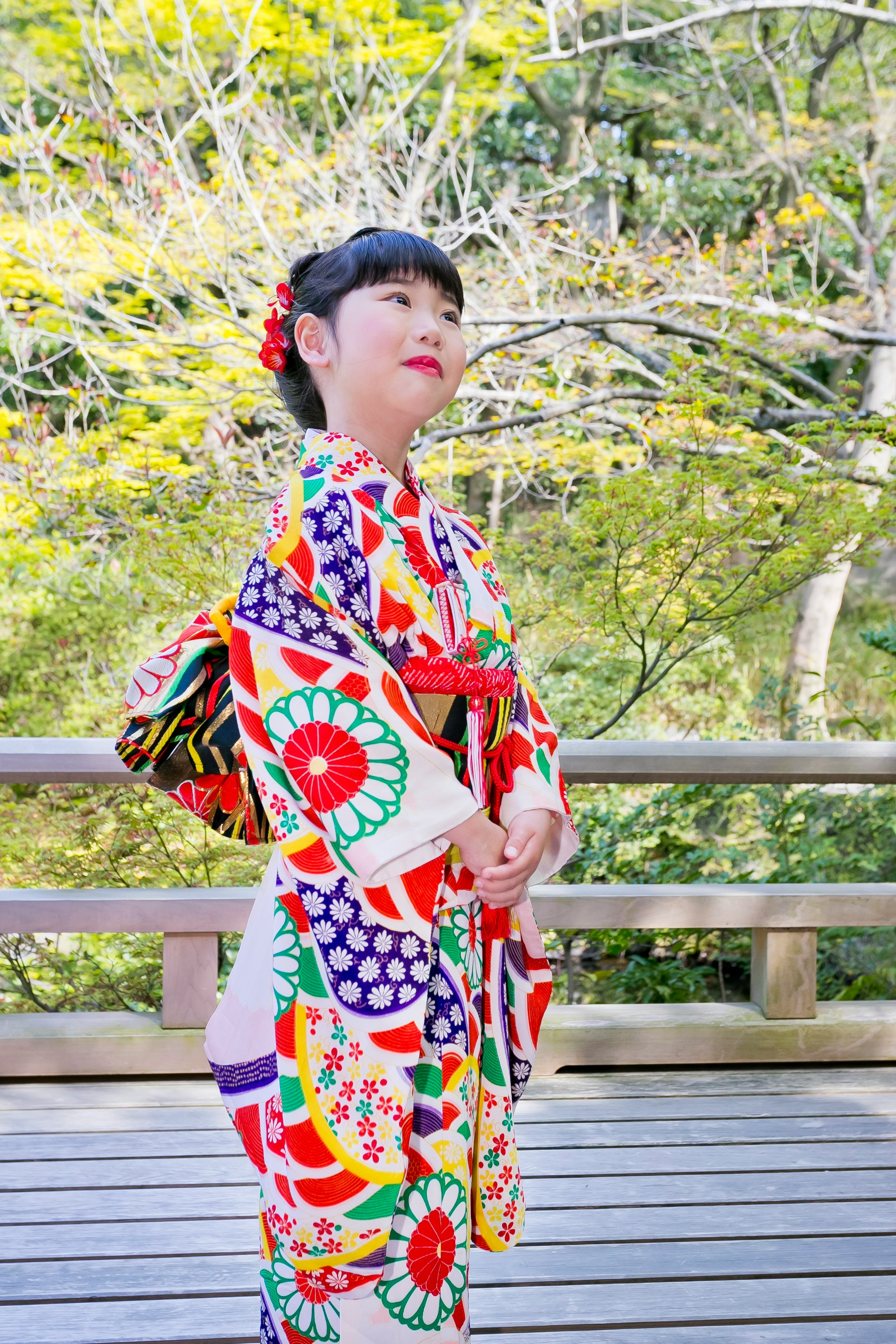 春の庭で立つ子どもの和柄着物姿
