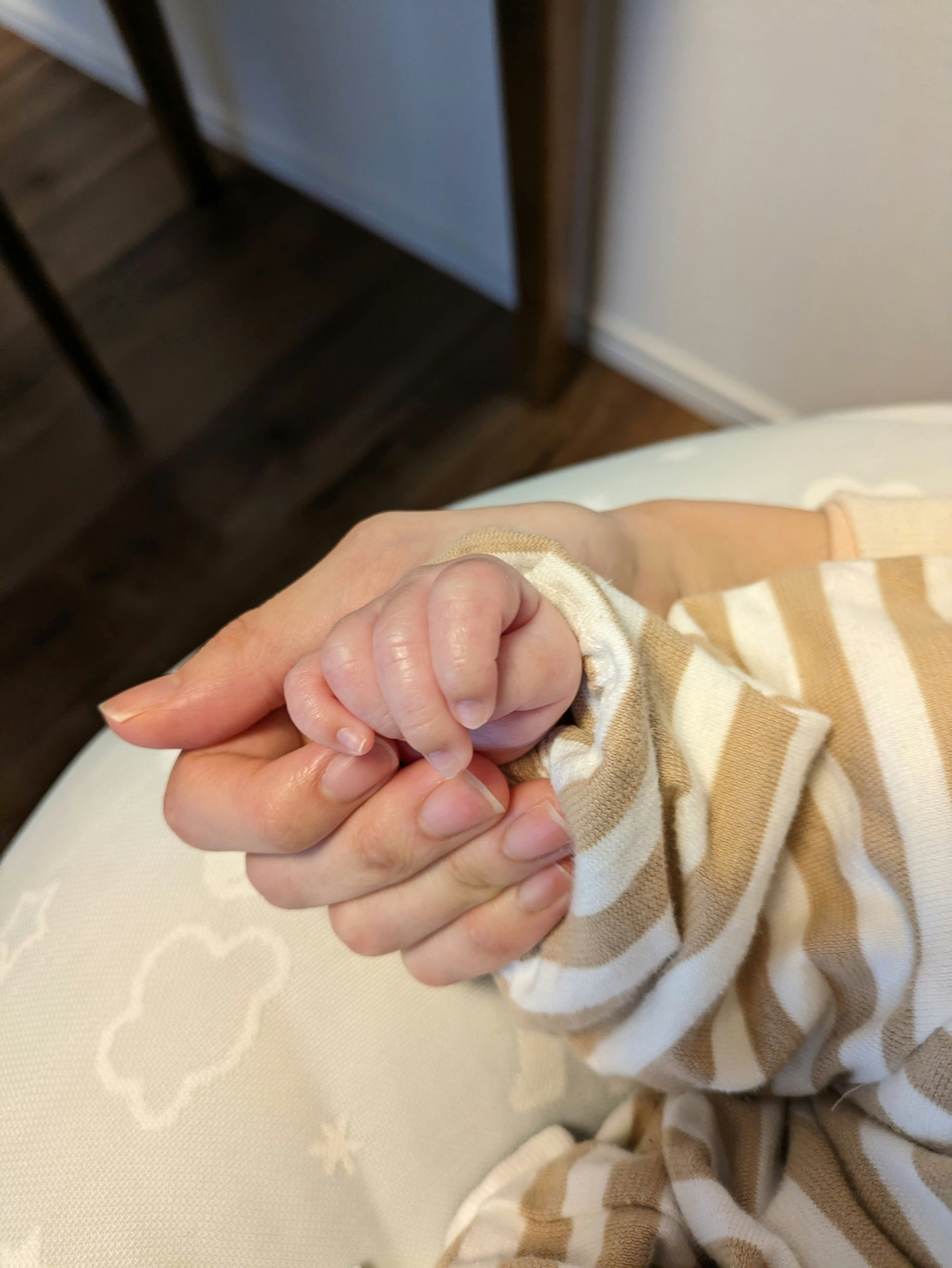 包み込む手と赤ちゃんの握る瞬間