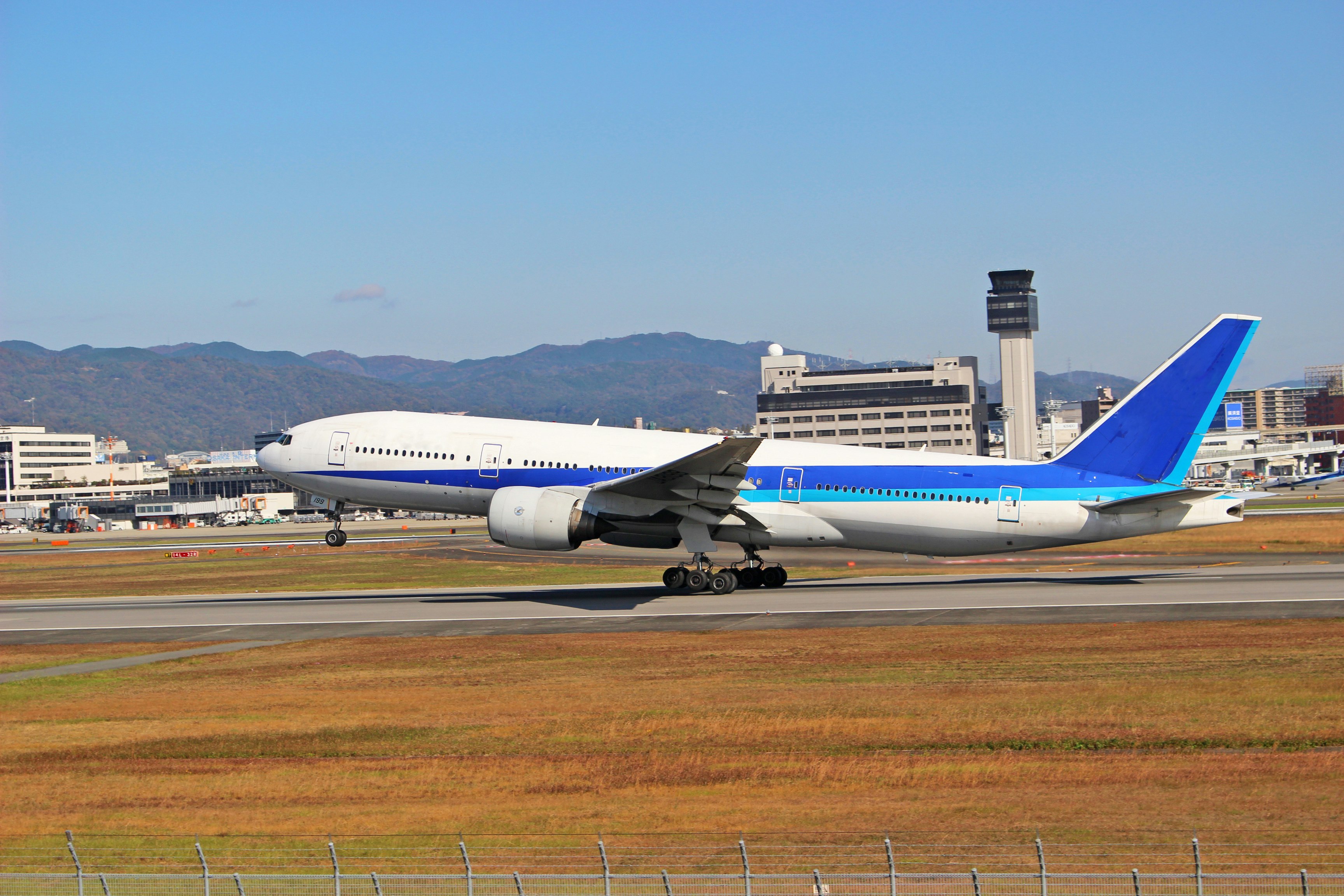 passenger airplane taxiing on a runway with an airport control tower