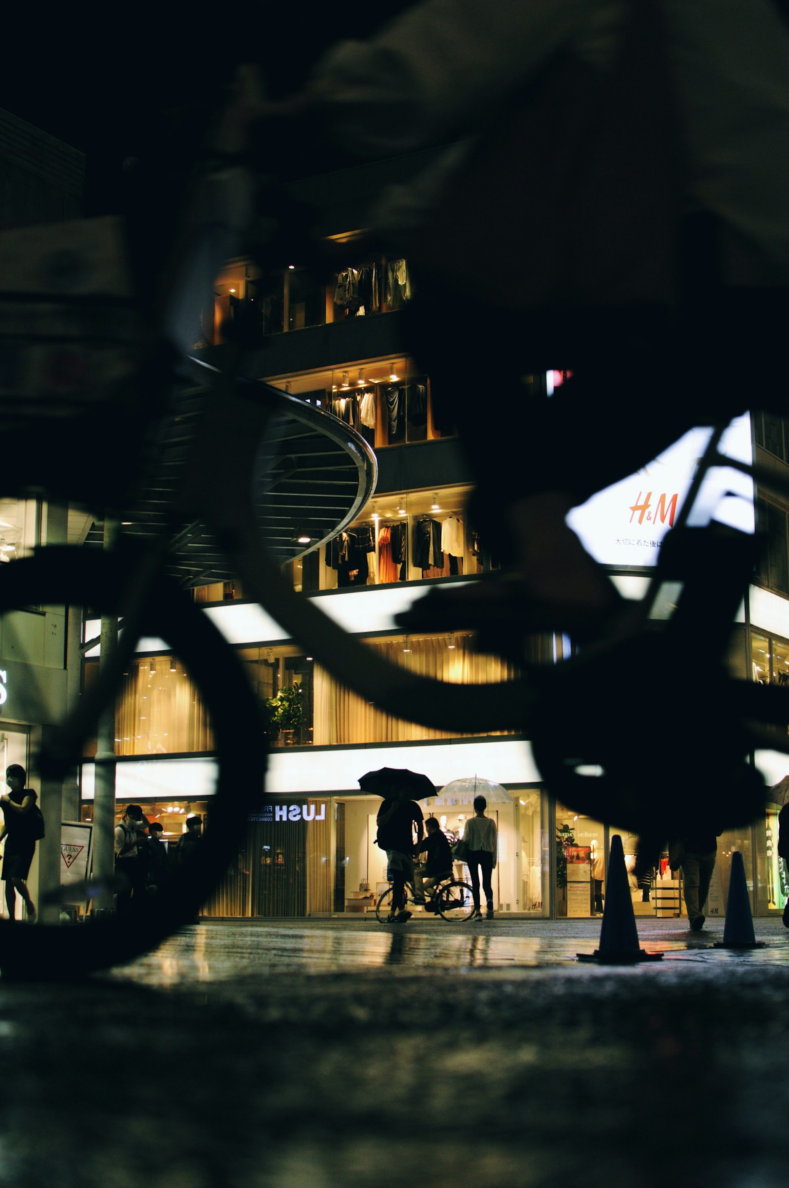 Silhouette di una bicicletta che passa con edifici illuminati sullo sfondo di notte