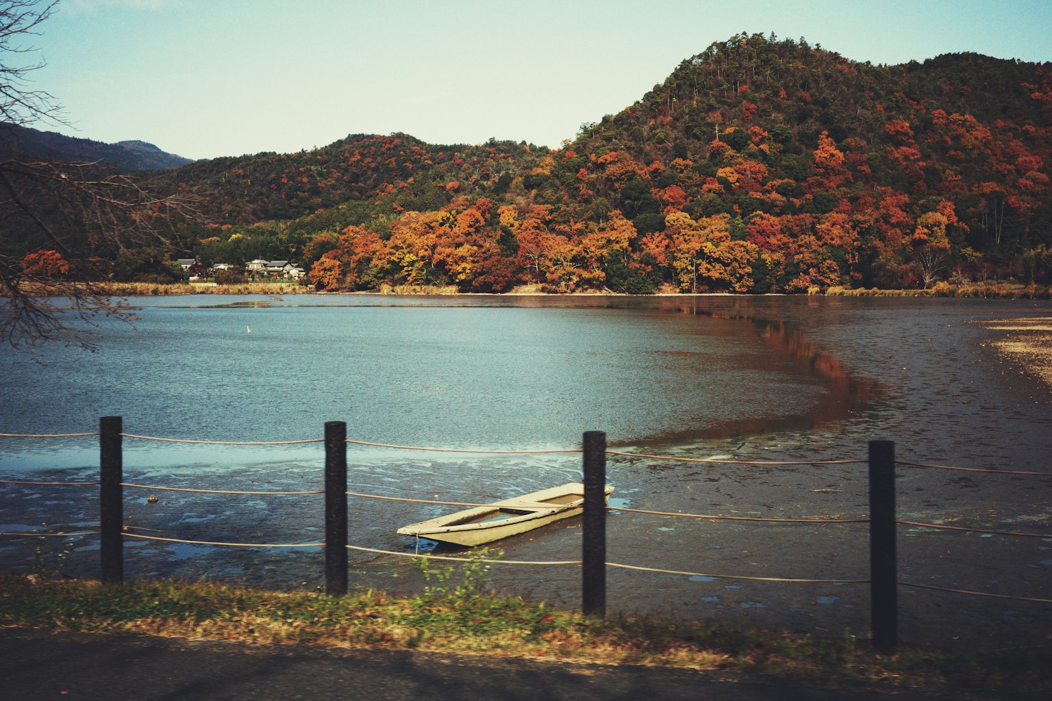 Un lago tranquillo con un fogliame autunnale vibrante sullo sfondo e una piccola barca