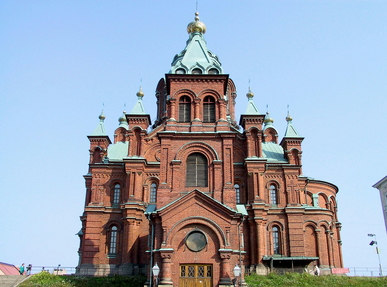 Beautiful red brick church featuring golden dome and green roofs