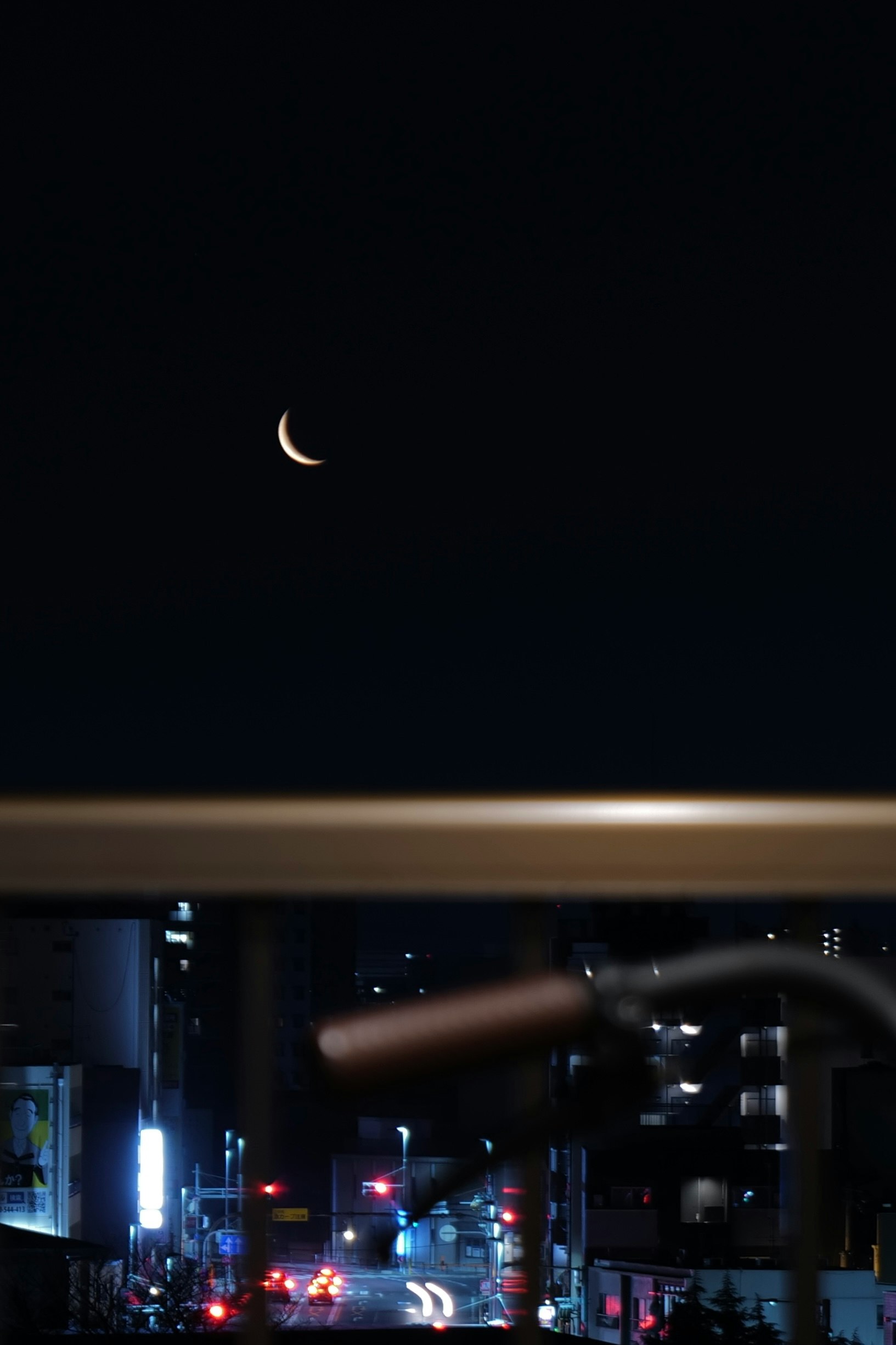 Vista nocturna de la ciudad con la luna desde un balcón