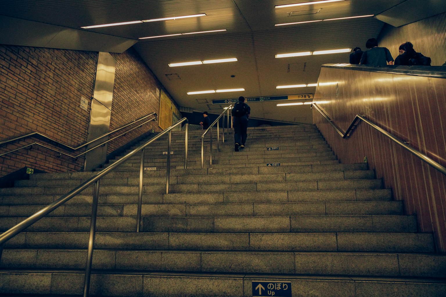 Persona subiendo escaleras de metro con iluminación moderna y diseño