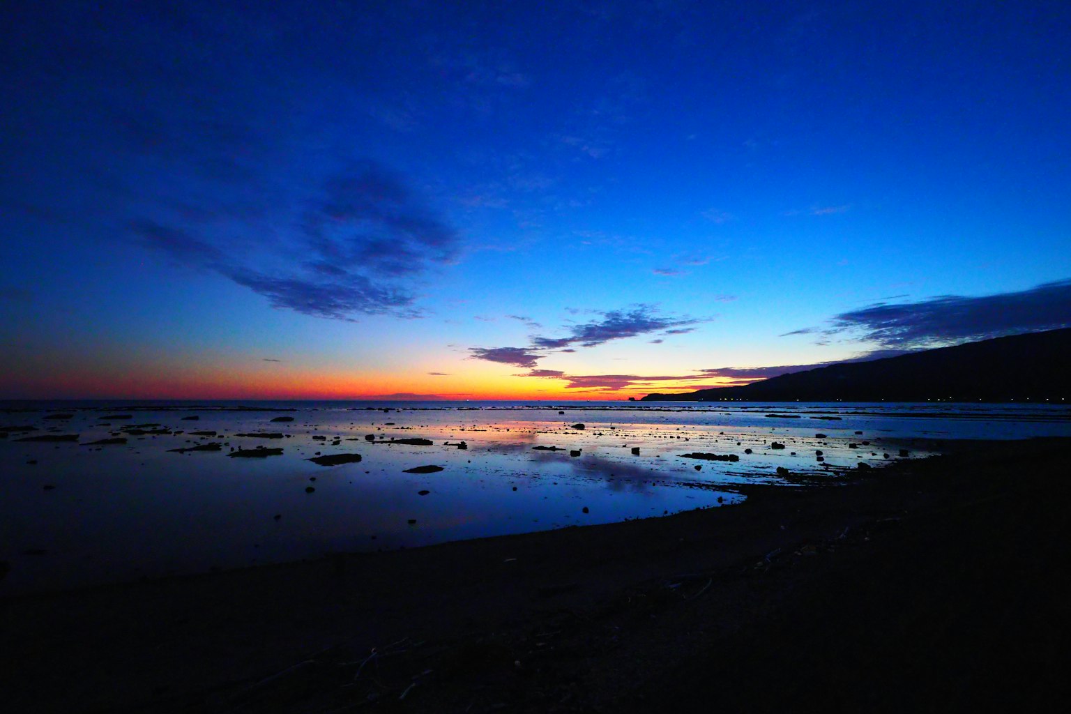 Hermoso atardecer sobre el océano con cielo azul profundo y contraste de luz naranja