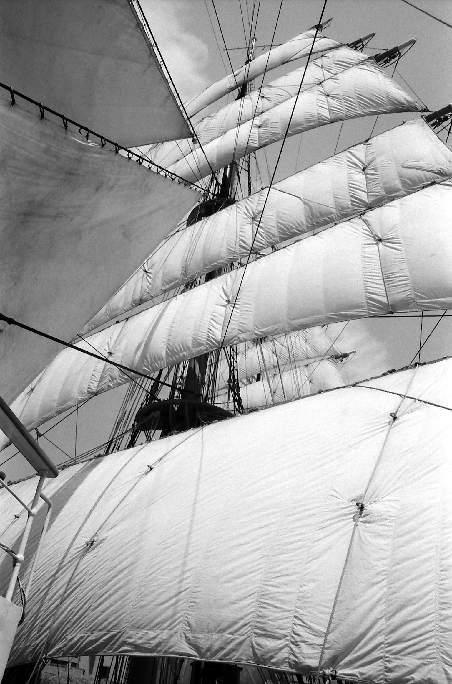 Black and white image of a tall ship with sails unfurled against the sky