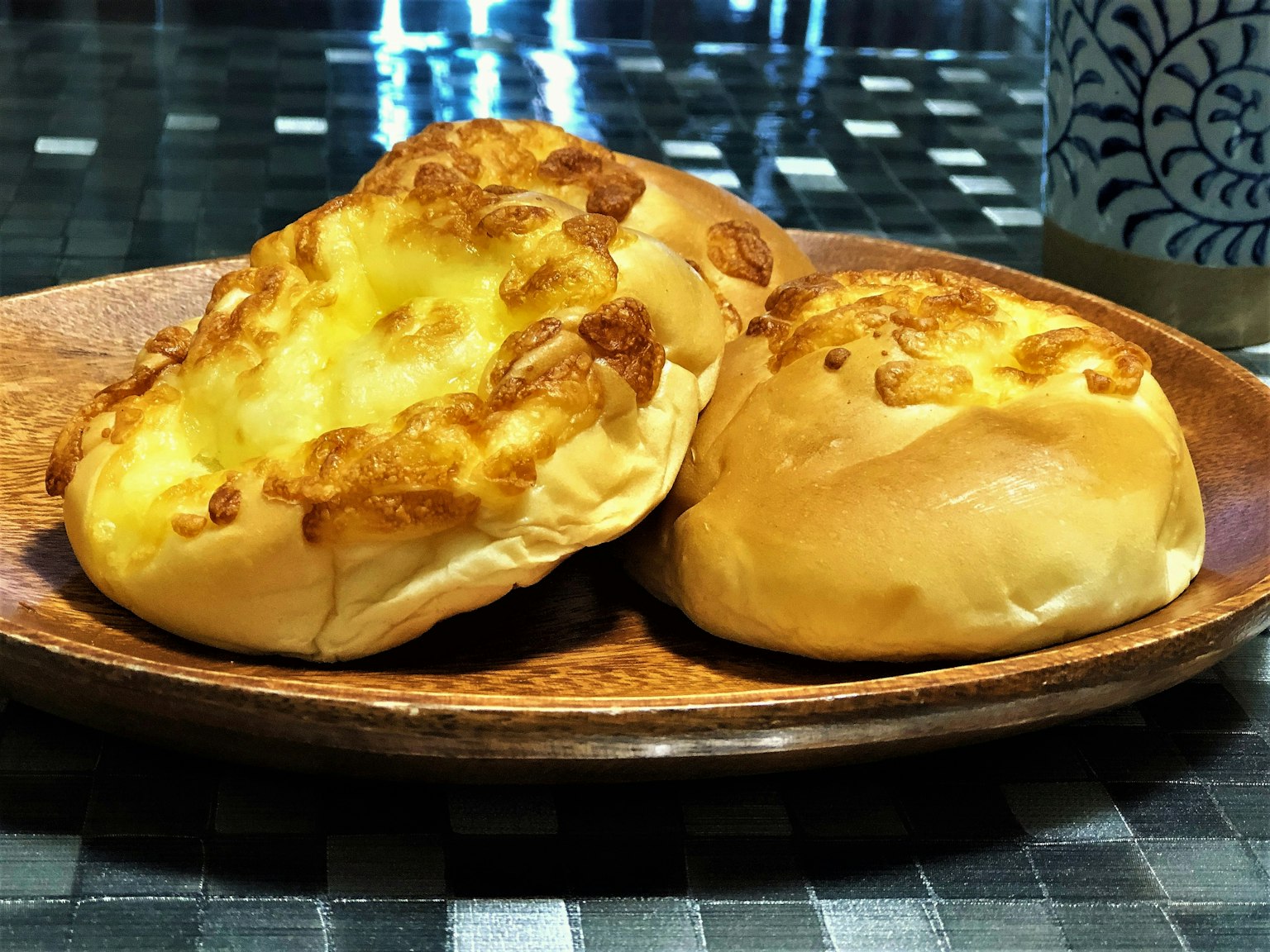 Deux petits pains sur une assiette en bois l'un garni de fromage