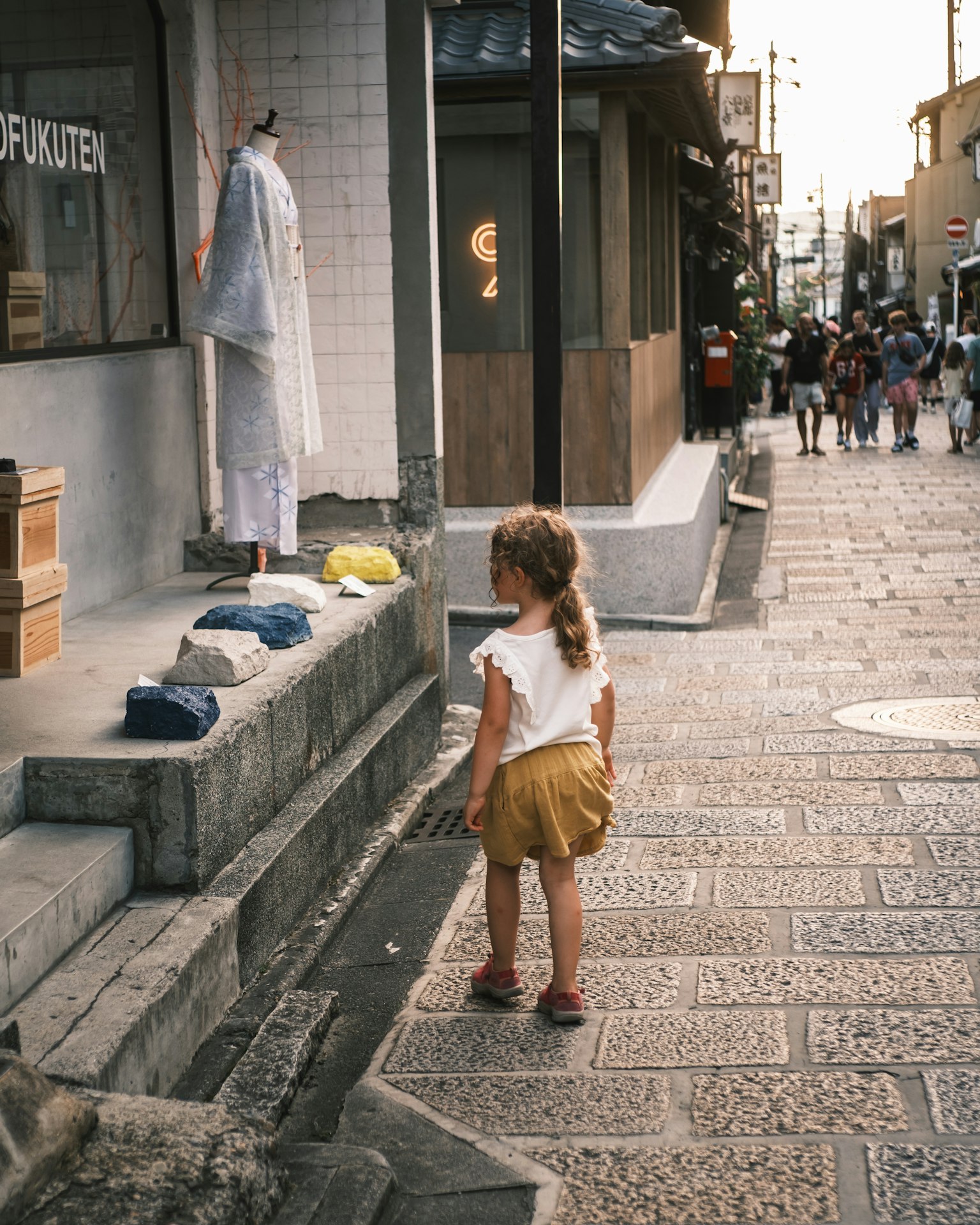 子供が店の前で立っている風景 石畳の道と周囲の人々
