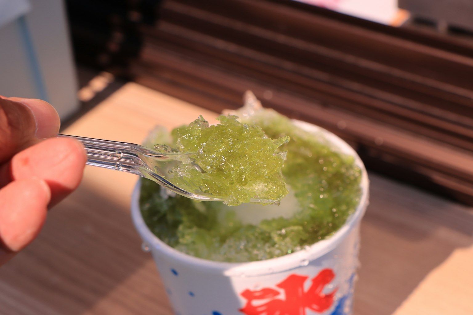 Una mano sosteniendo un tenedor sacando hielo raspado verde