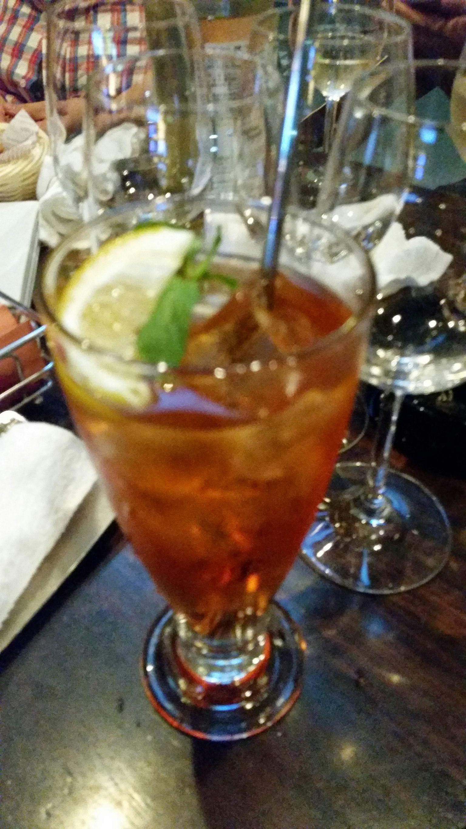 A glass of iced tea garnished with lemon and mint leaves
