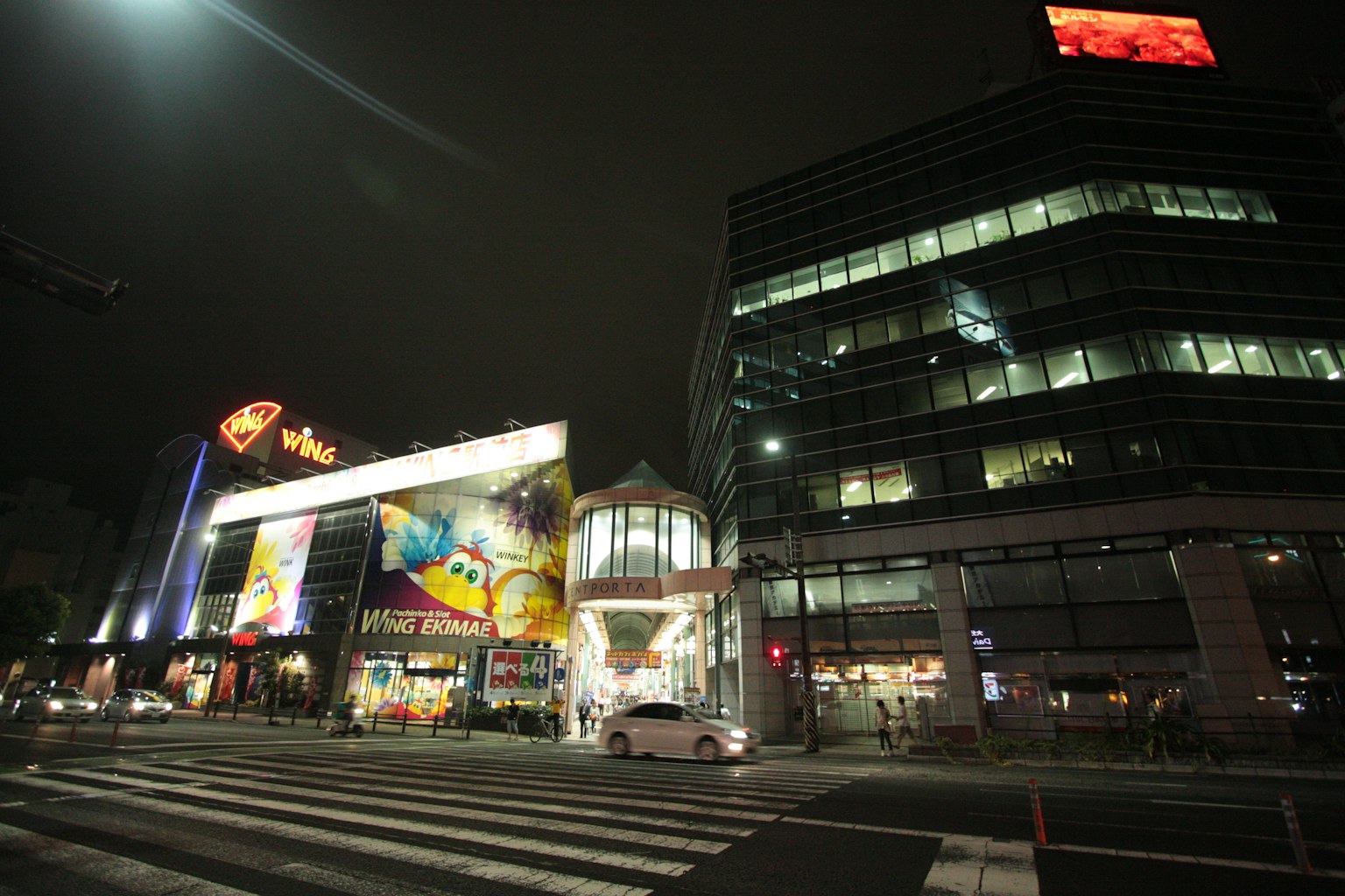 Paysage urbain nocturne avec des panneaux lumineux et un passage piéton