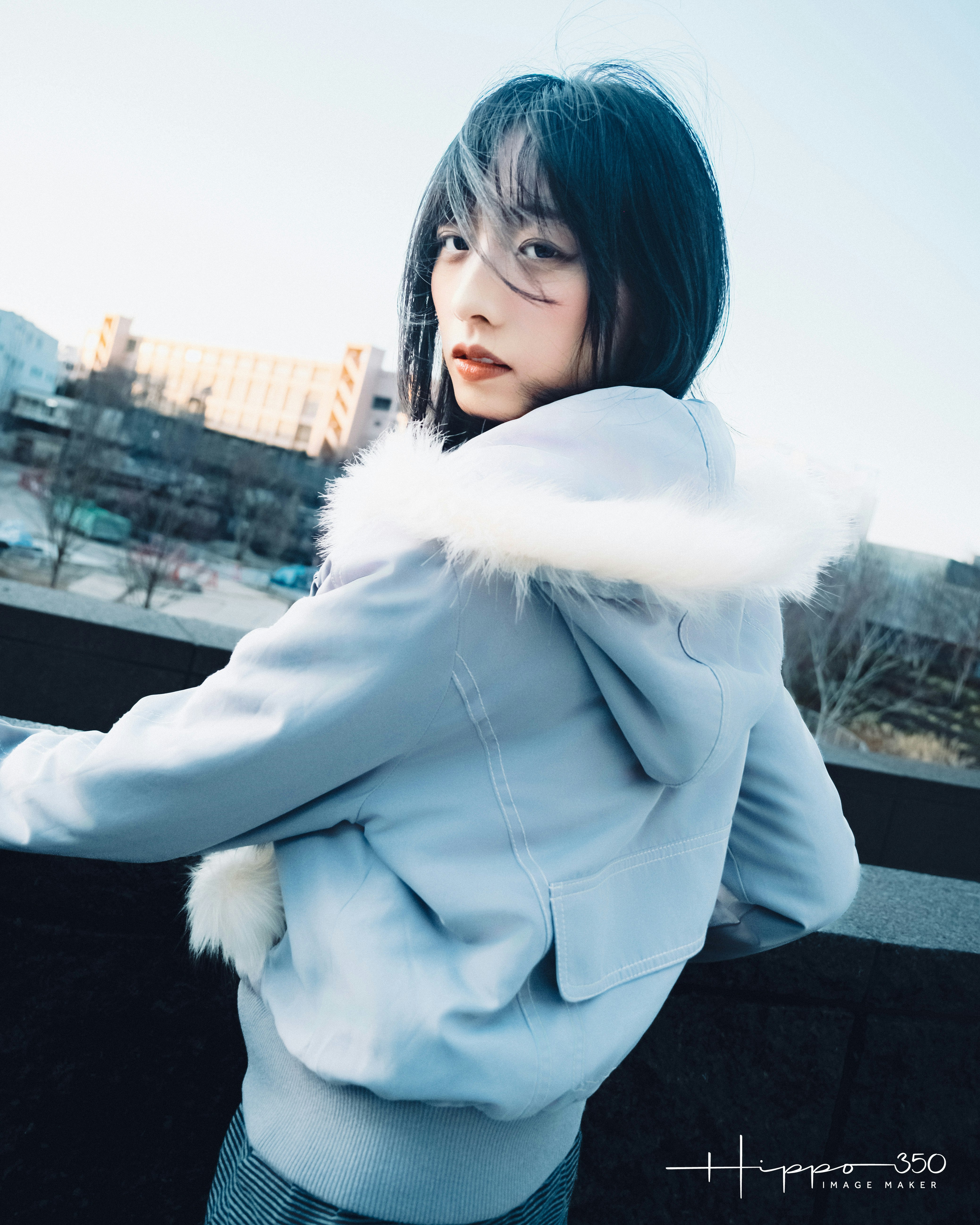 屋上で白いファー付きコートを着た女性のポートレート