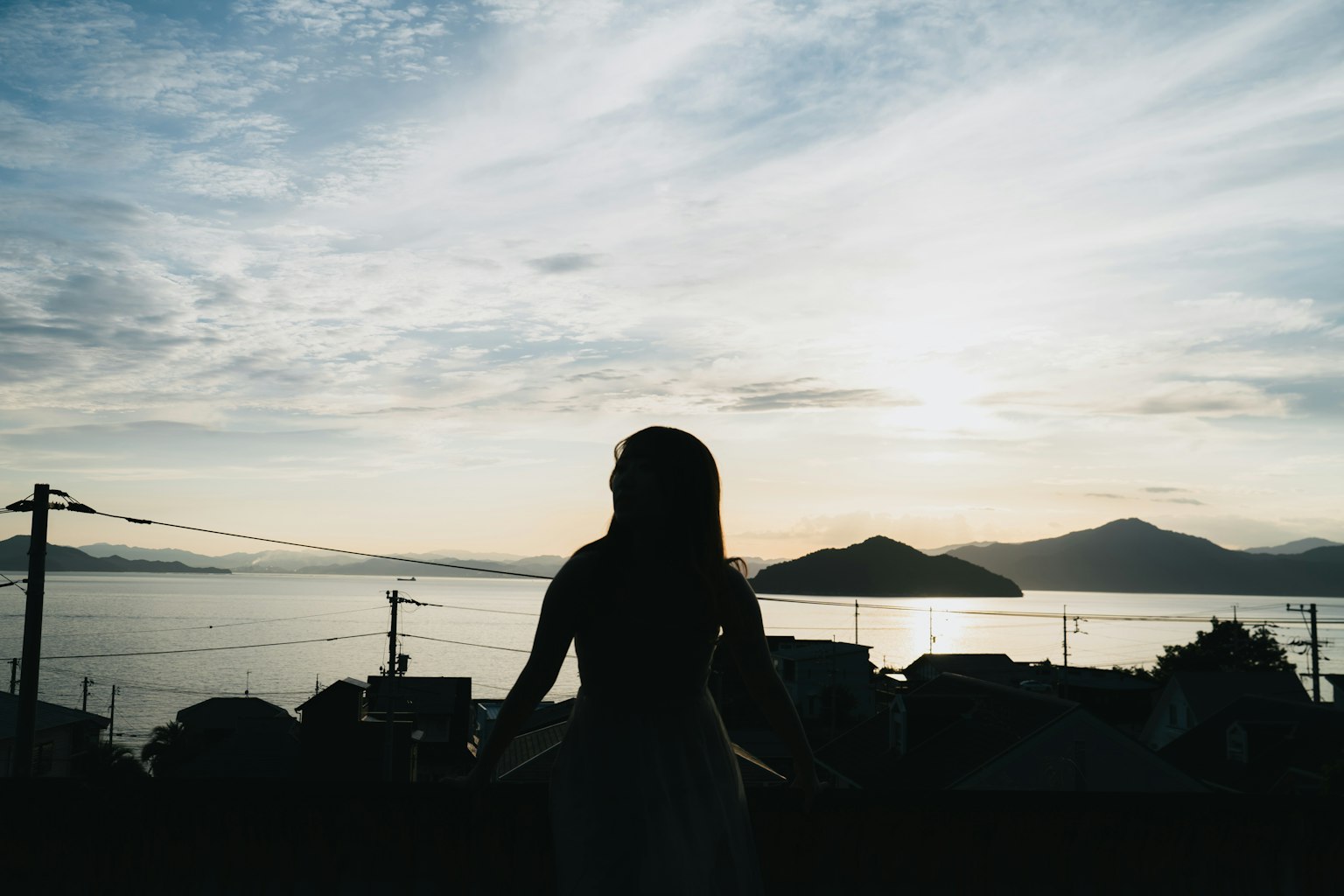 Silhouette wanita melawan latar belakang matahari terbenam dan lautan