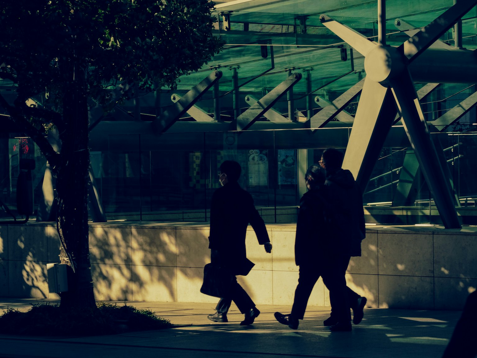 Figure in ombra che camminano in un contesto urbano con architettura moderna