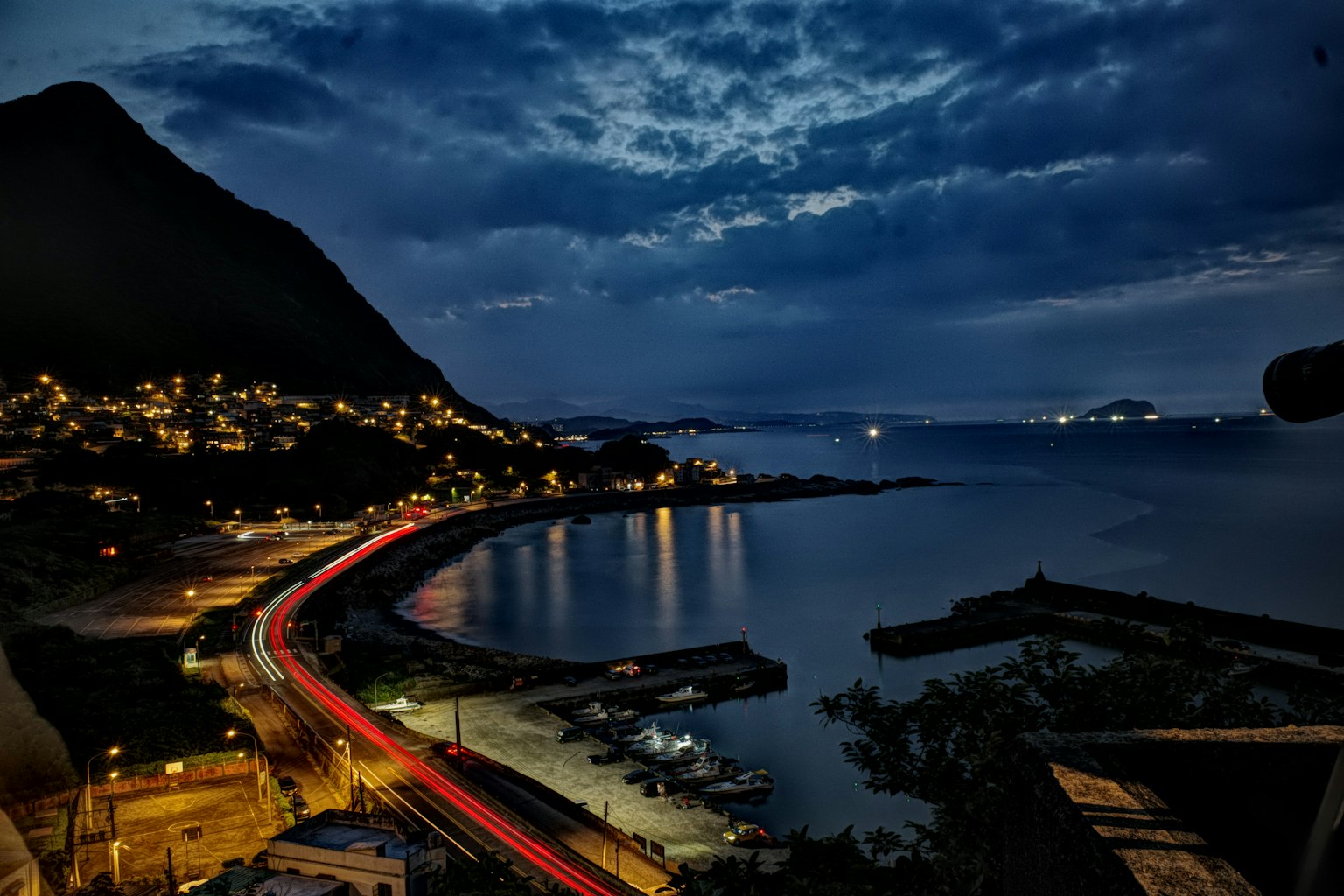 夜の海岸線と山の景色 港に停泊するボートと街の明かり