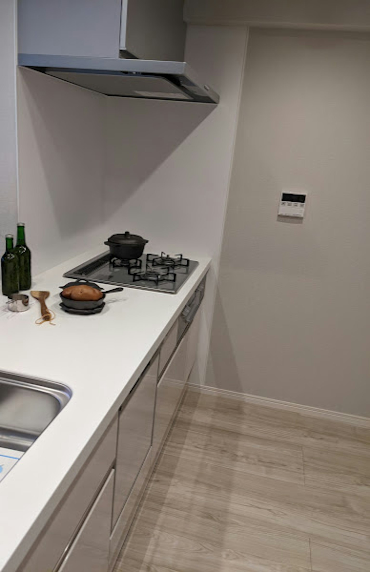 Cocina moderna con encimera blanca que presenta una olla y botellas verdes