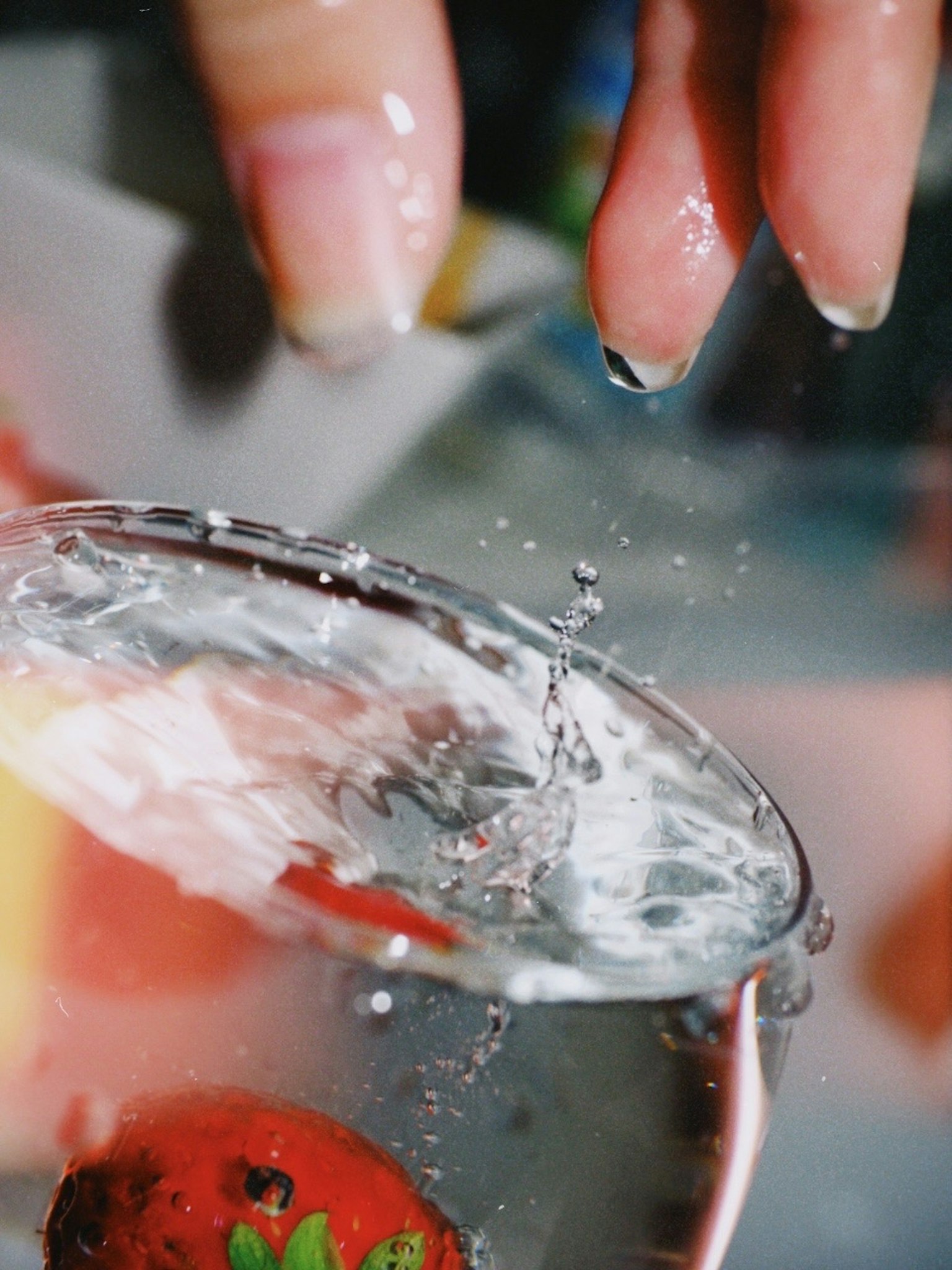 水しぶきが上がるグラスとイチゴの近くにある手