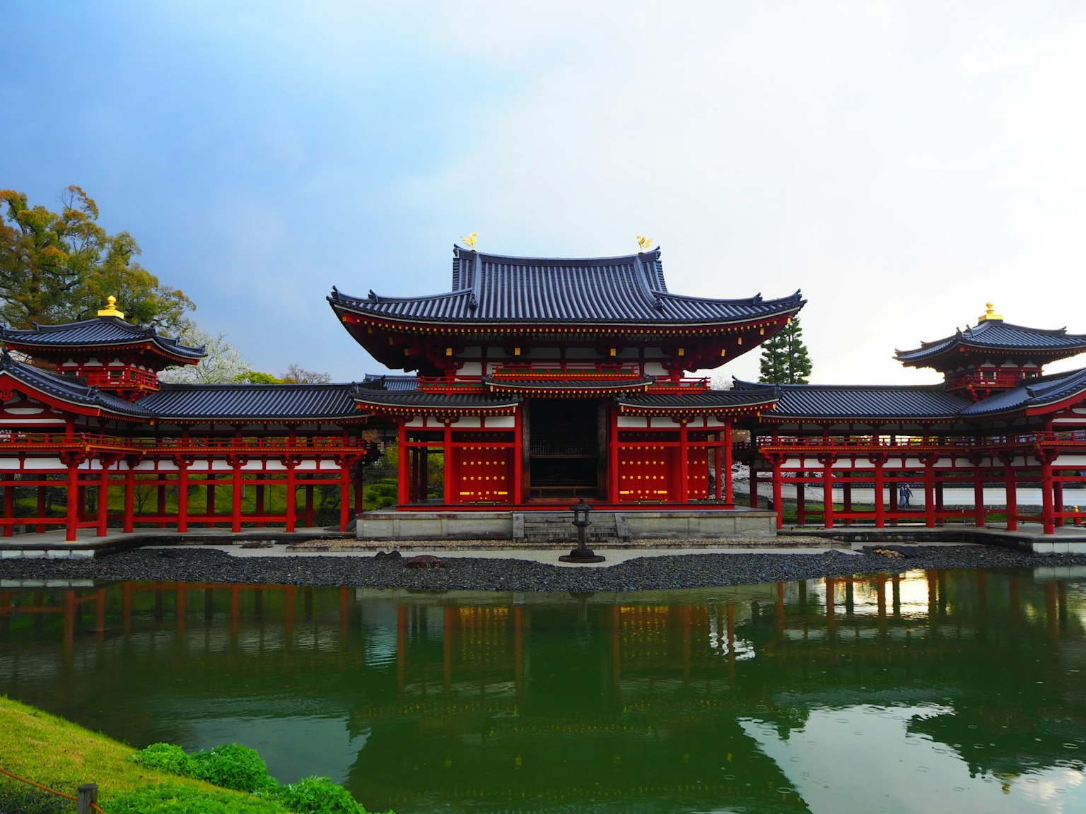 美麗池塘前的紅色寺廟建築