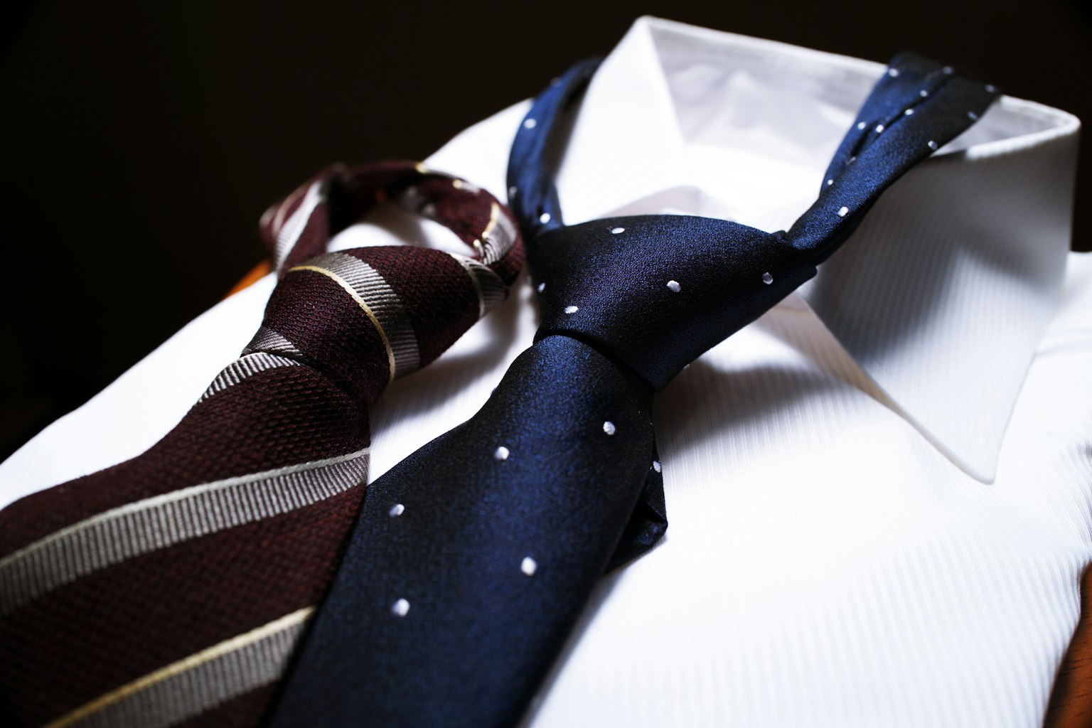 Blue polka dot tie and brown striped tie on a white shirt