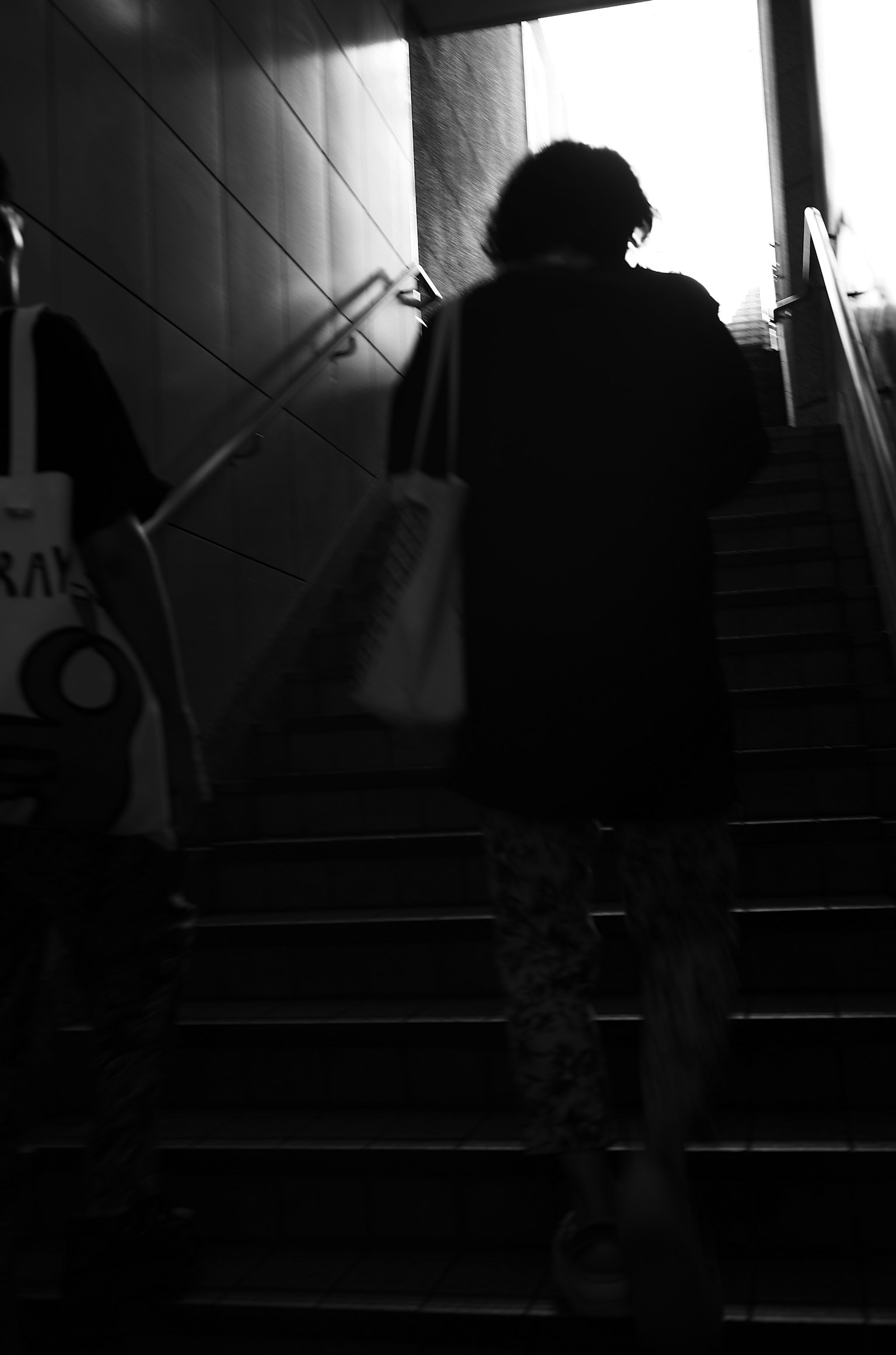 Silhouette of a person ascending stairs with bright exit light