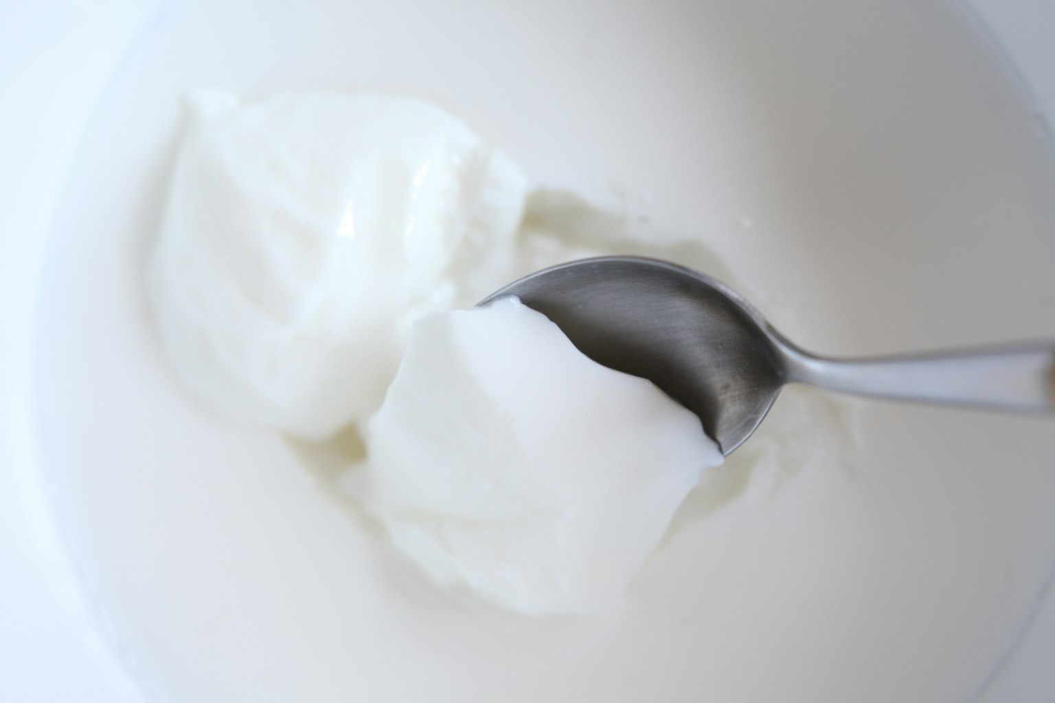 Yogur cremoso en un tazón blanco con una cuchara