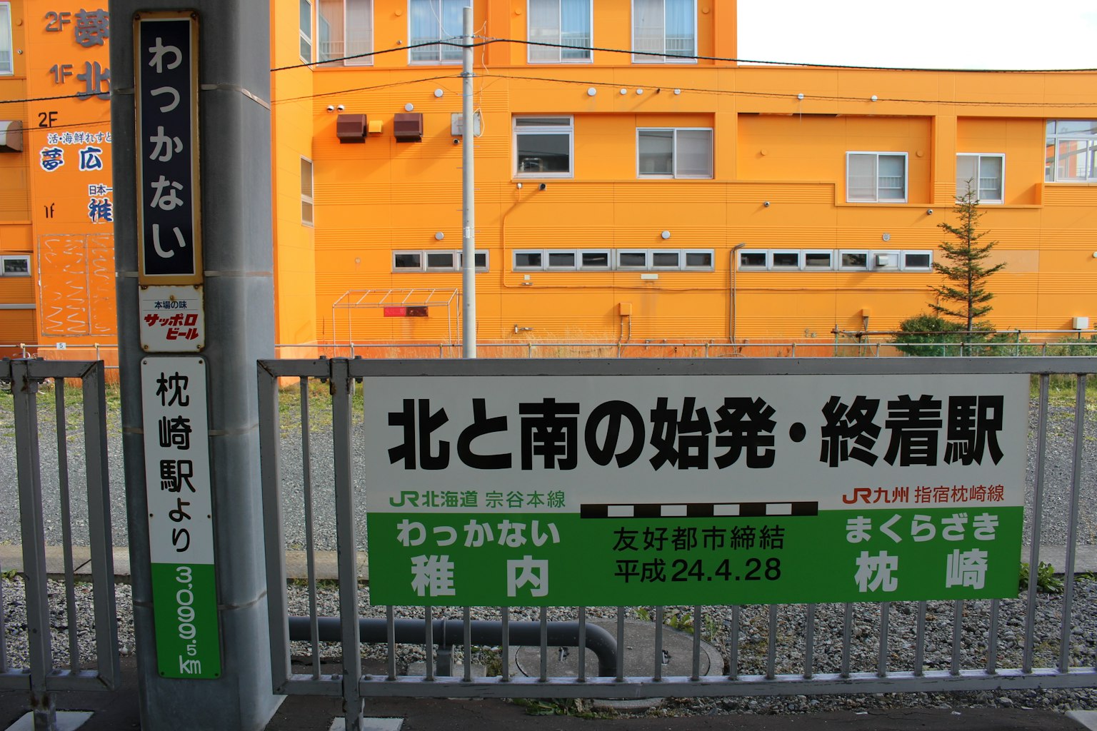 Cartel de la estación de Wakkanai con fondo de edificio naranja