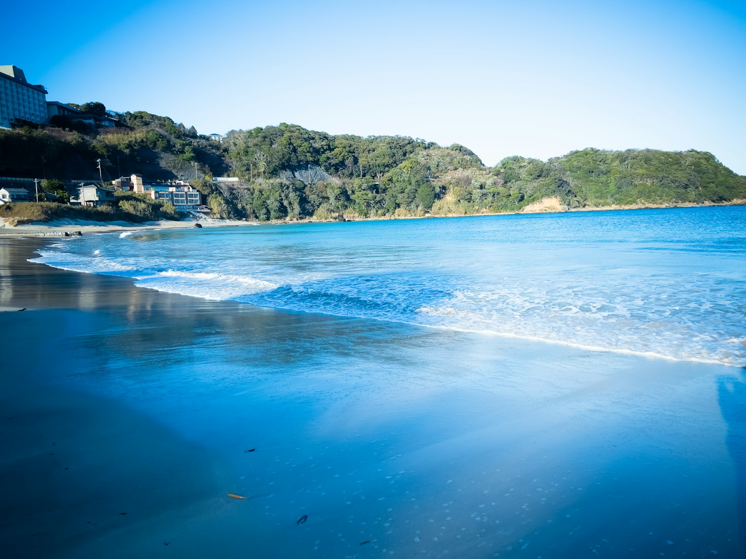 Malersicher Blick auf einen blauen Ozean mit sanften Wellen und grünen Hügeln