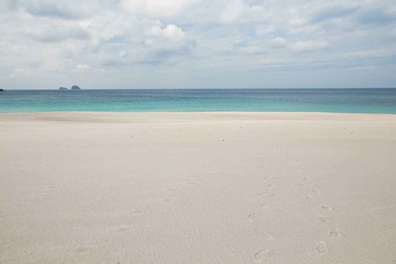 Calm sea and white sandy beach with cloudy sky