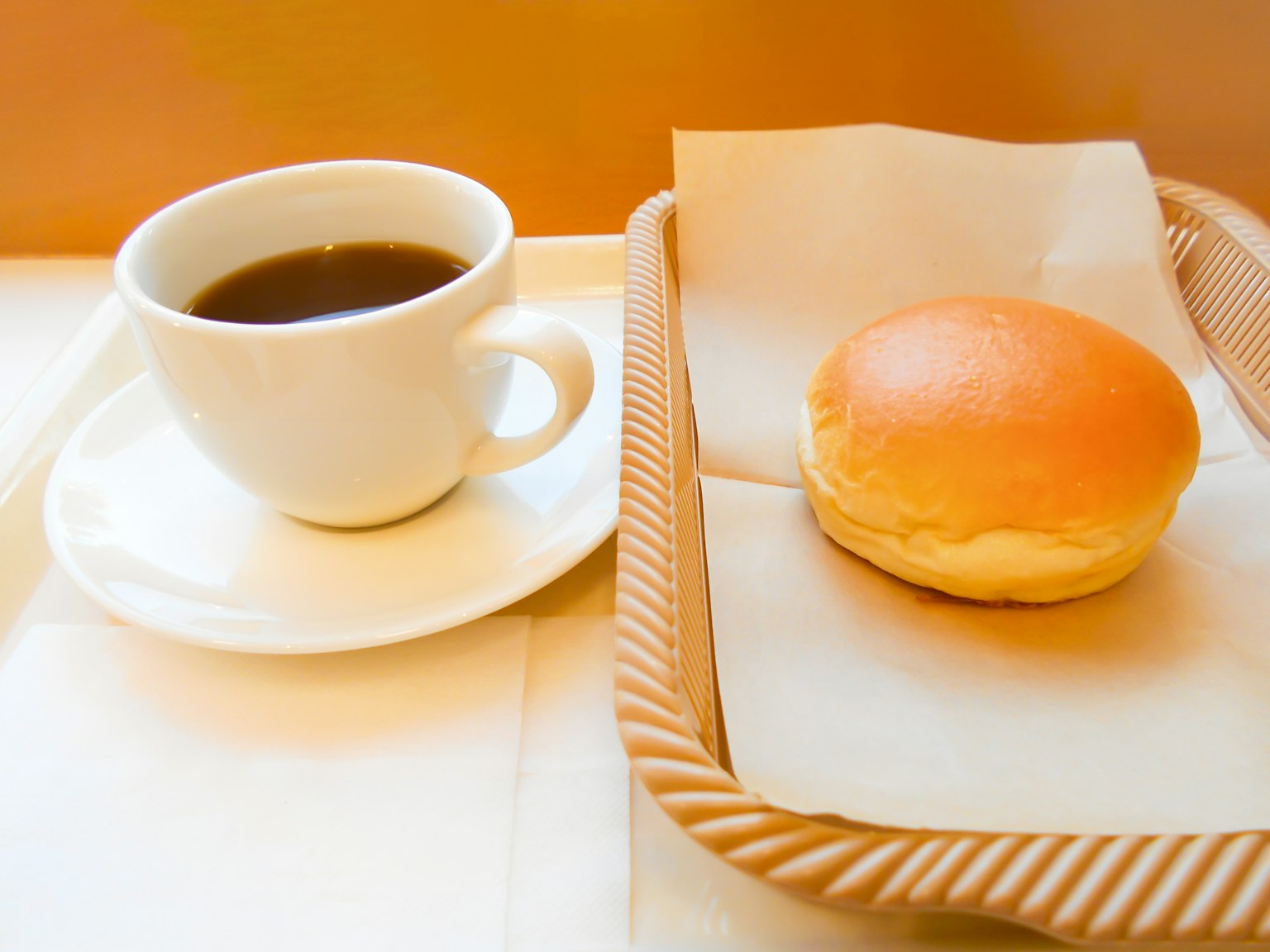 Bild einer Tasse Kaffee und einem Brötchen auf einem Tablett
