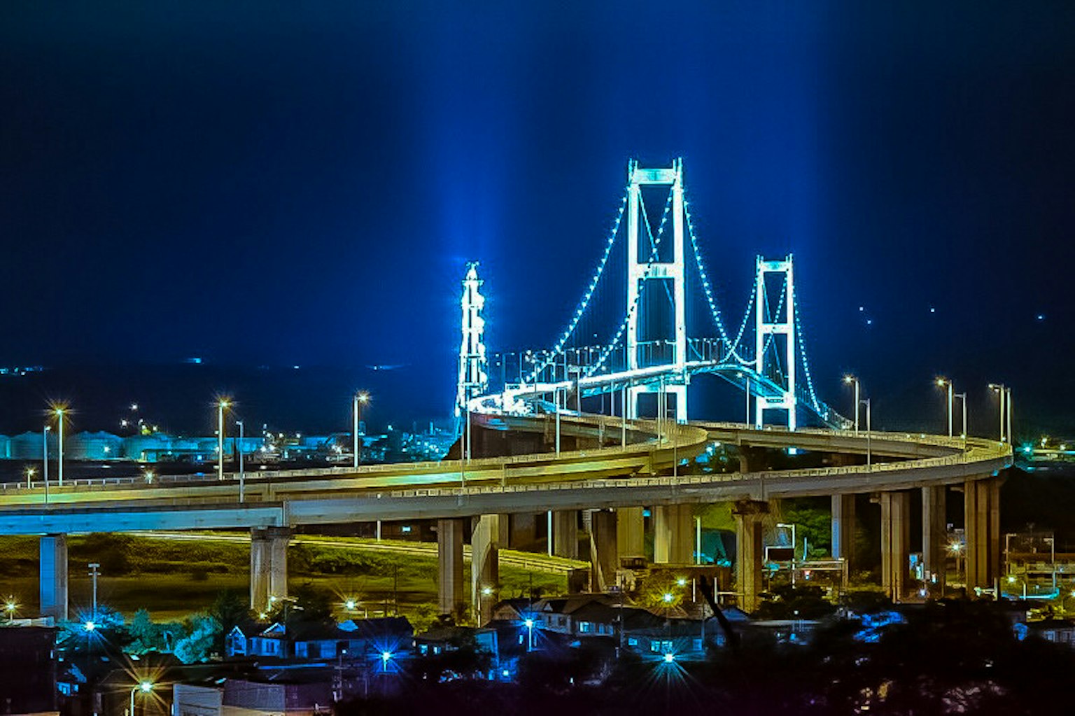Vista notturna di un ponte stupendo illuminato da luci blu e traffico