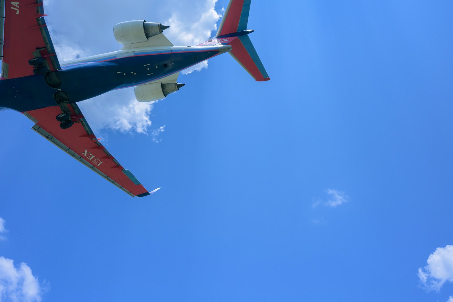 Flugzeug fliegt unter einem blauen Himmel mit Wolken