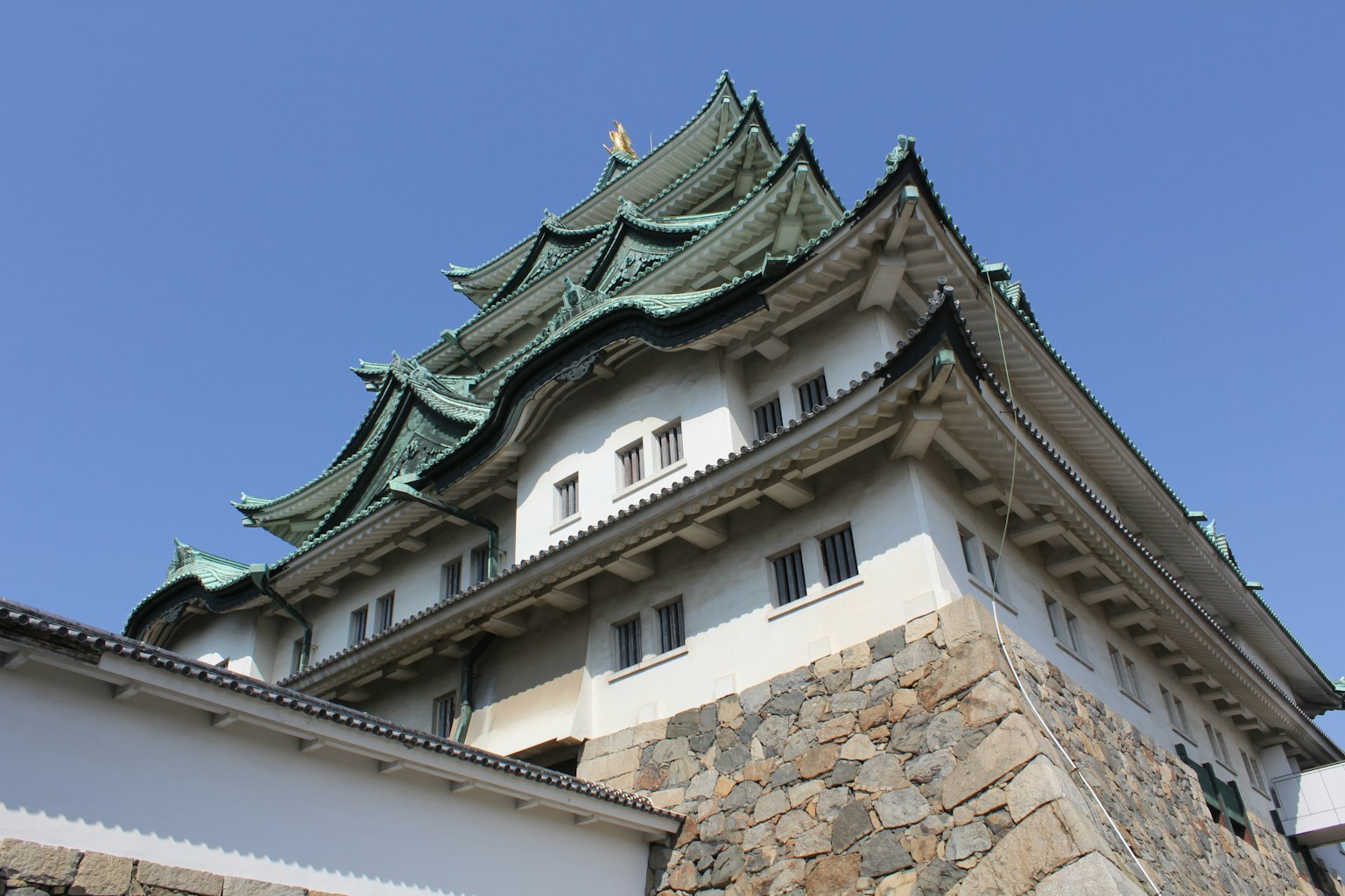 Foto, die das schöne Dach und die Steinbasis des Nagoya-Schlosses aus einem einzigartigen Winkel zeigt