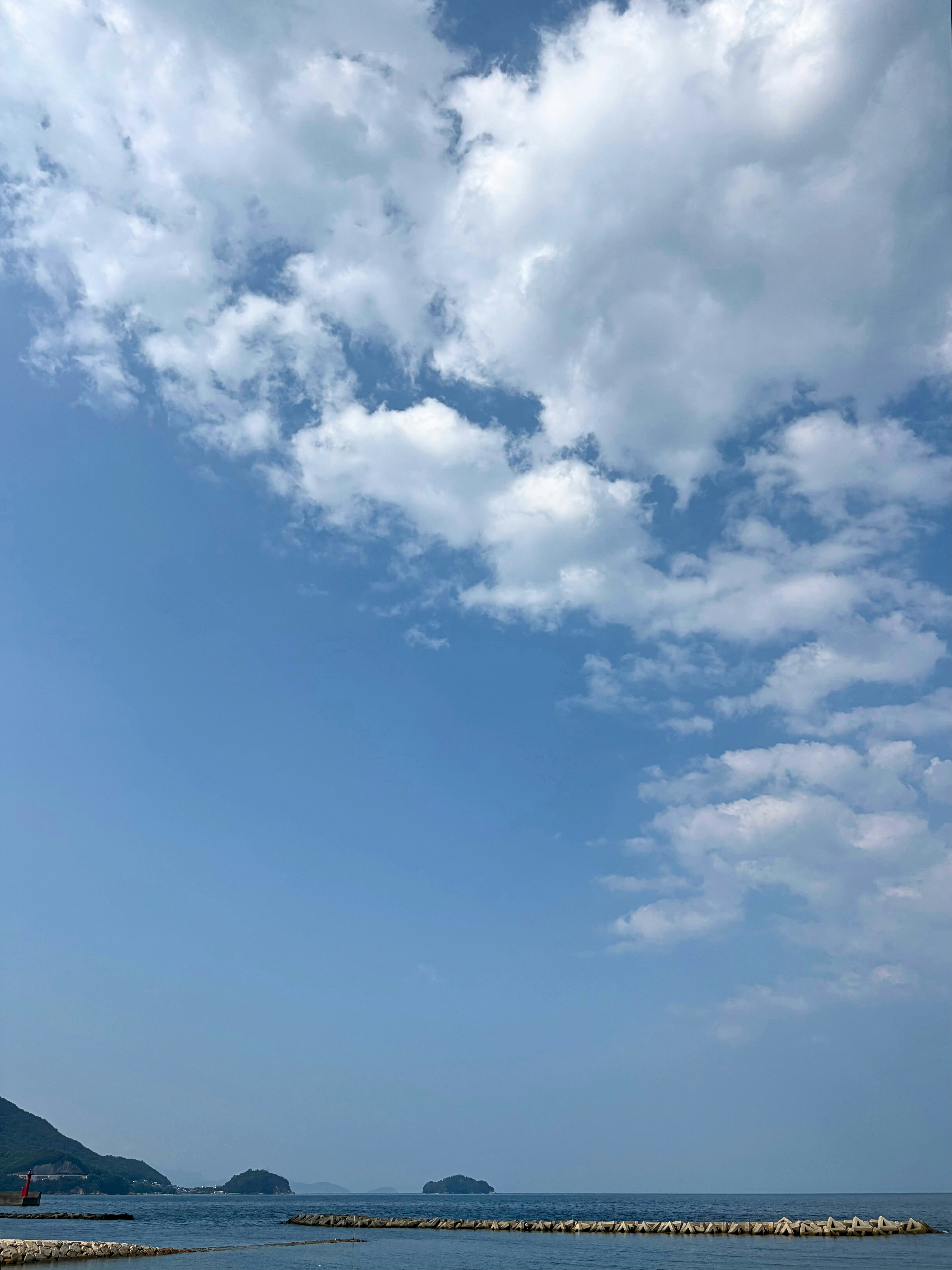 青い空と雲の下、瀬戸内海の海面と島影