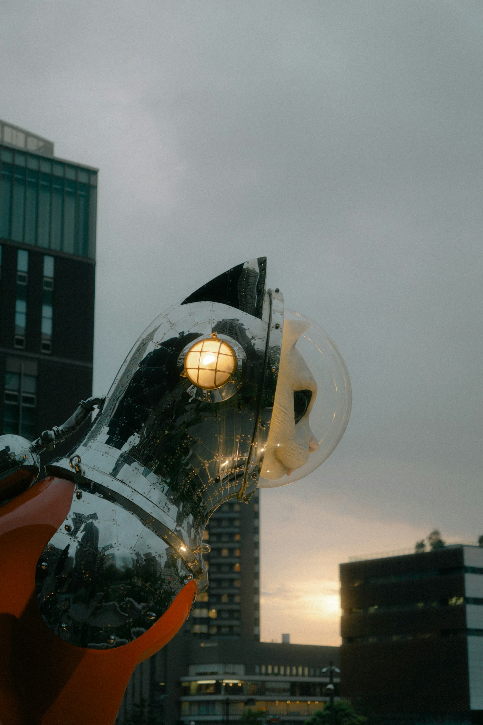 Futuristic sculpture with a glowing lamp and spherical elements against an urban backdrop