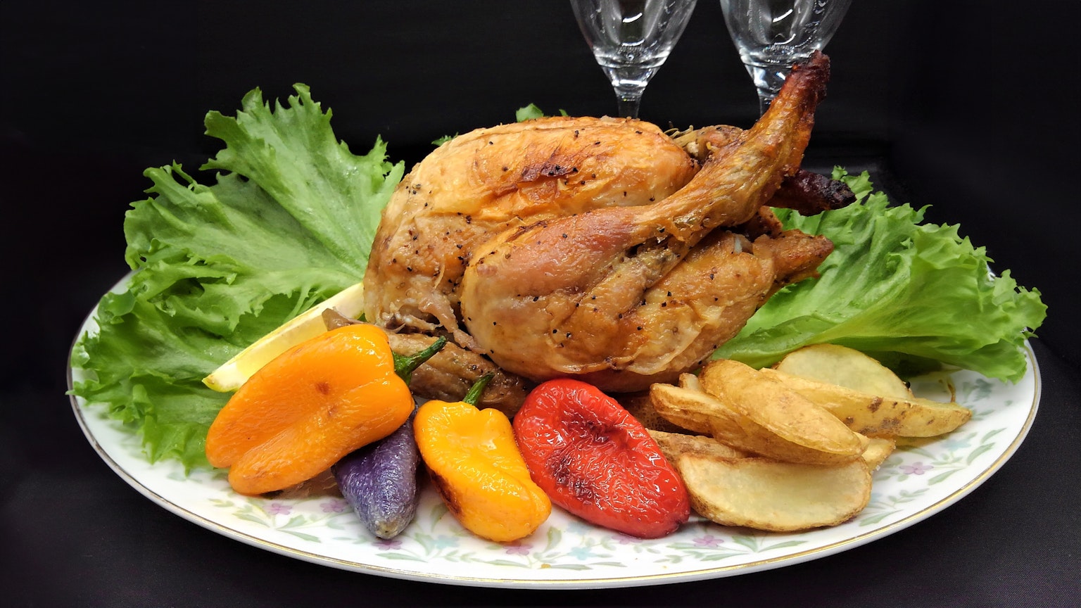 Roast chicken served on a platter with colorful vegetables and lettuce