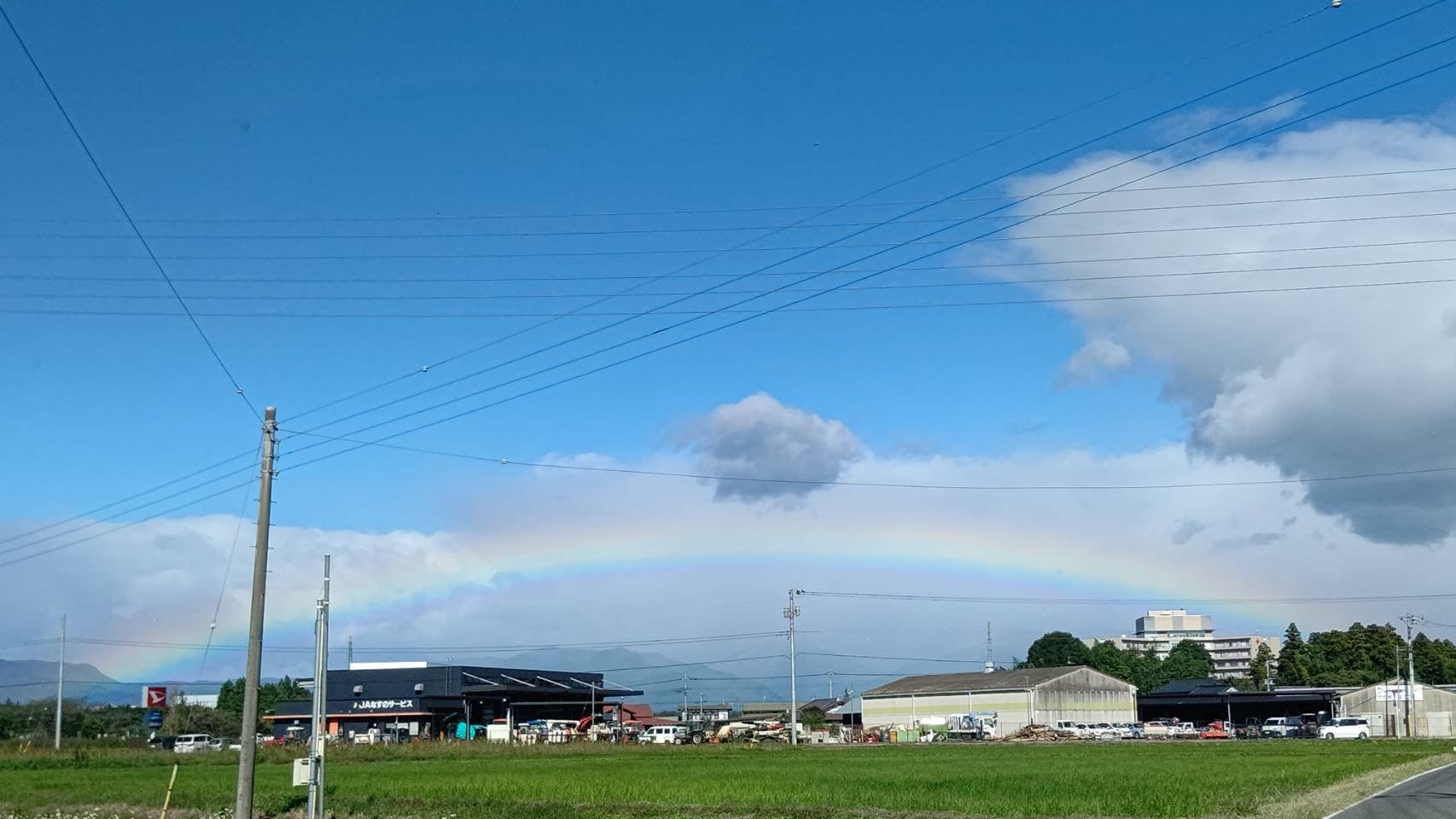 青空と雲の下に広がる山並みと田園風景