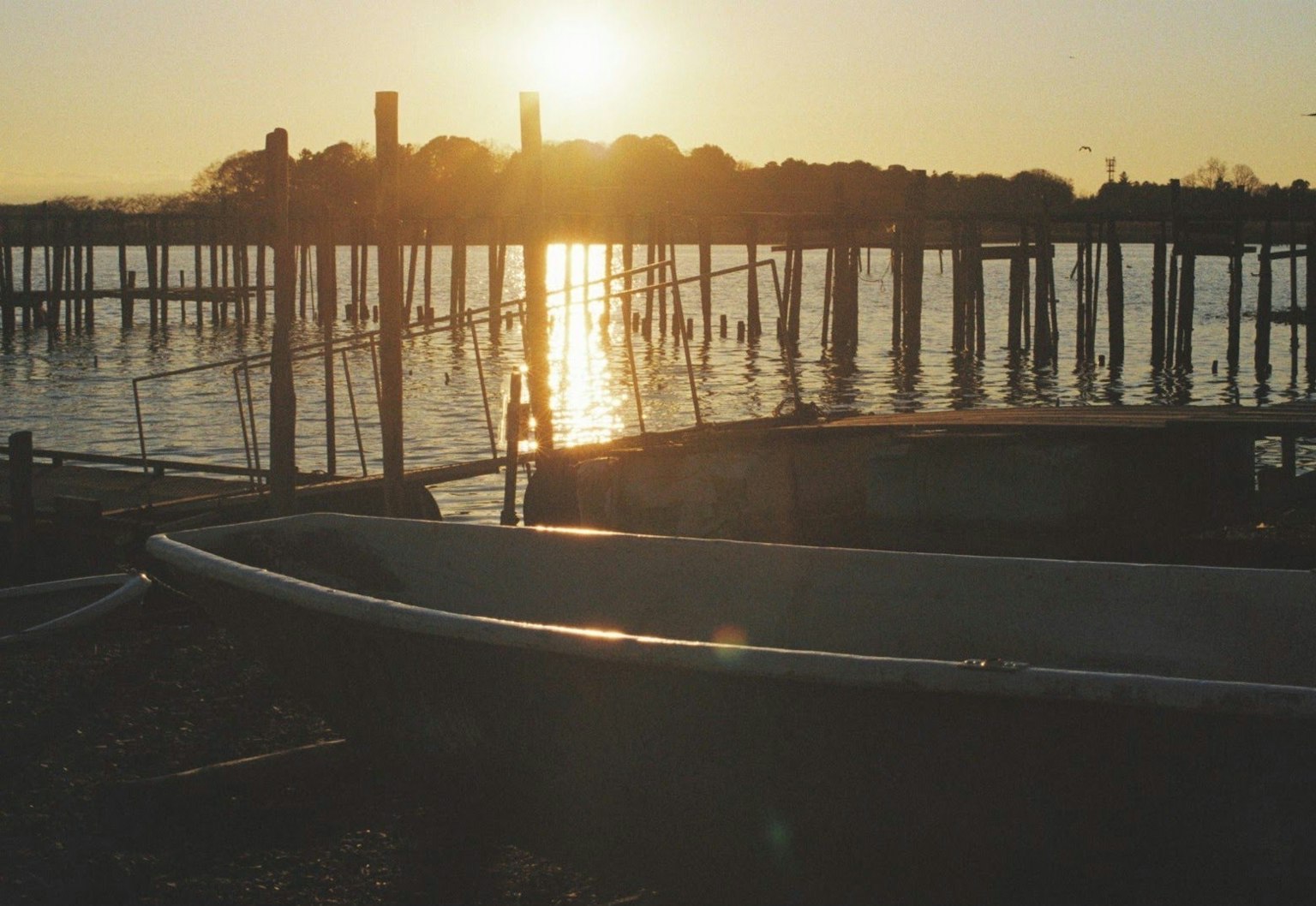 Boat and pier silhouette against sunset reflecting on water