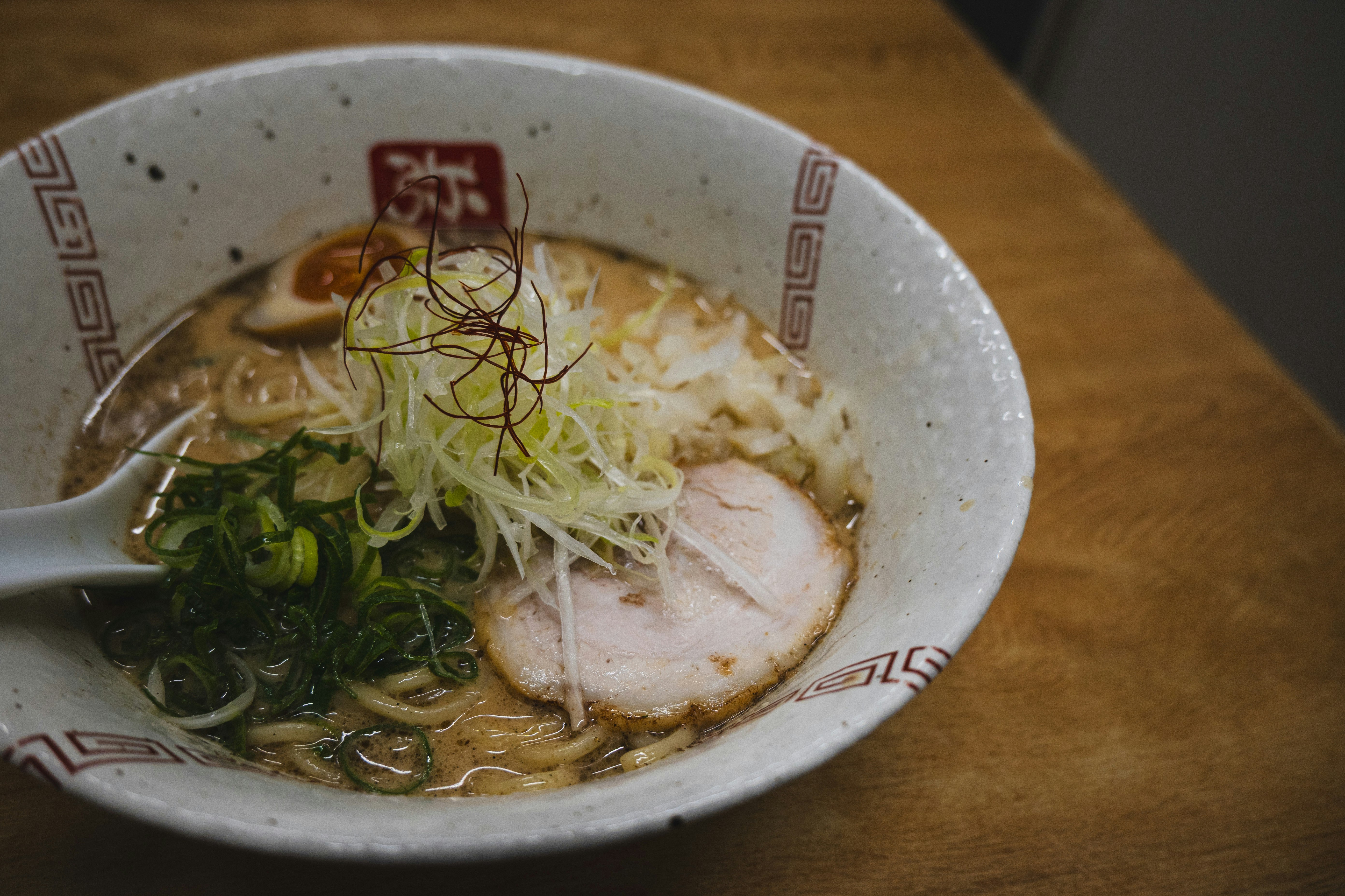 ラーメン鉢にのった豚チャーシューとネギ