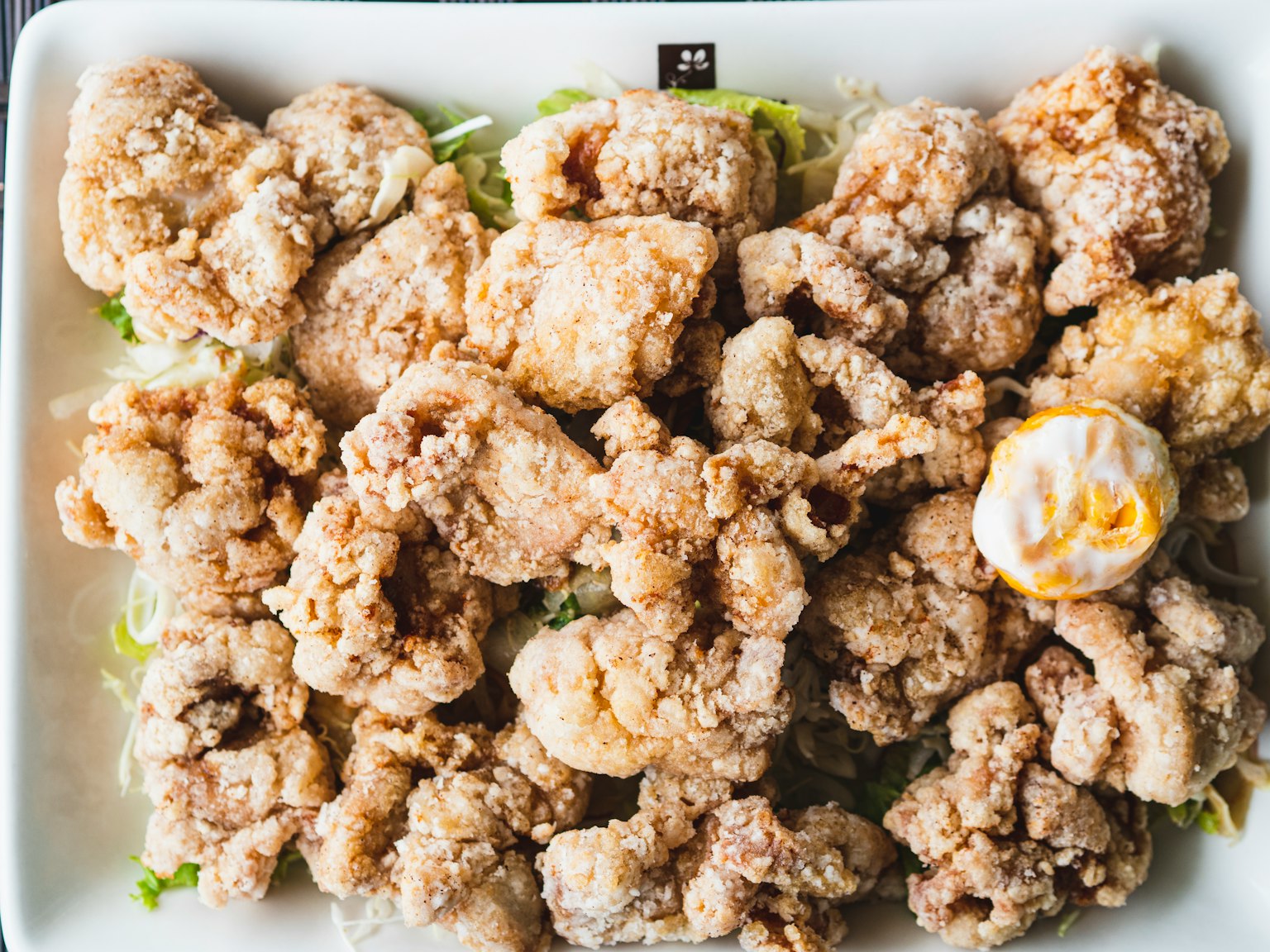 Plato de trozos de pollo frito crujiente adornado con lechuga