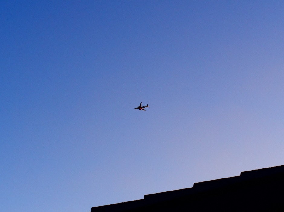 屋根の上に飛行機が見える夕暮れの空