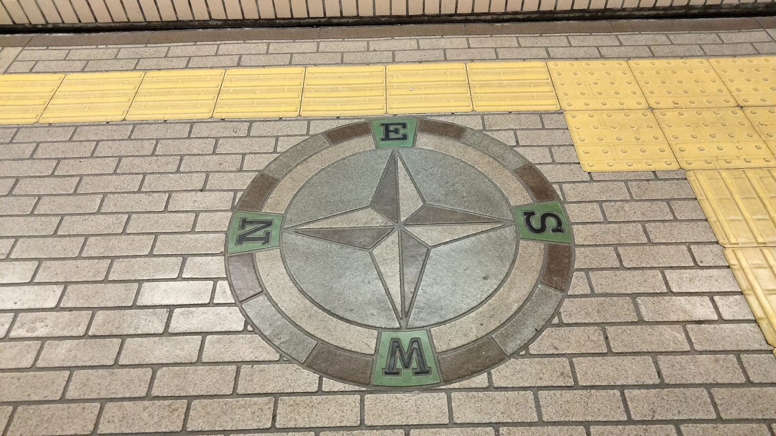 駅の床にあるコンパスデザインのモザイク