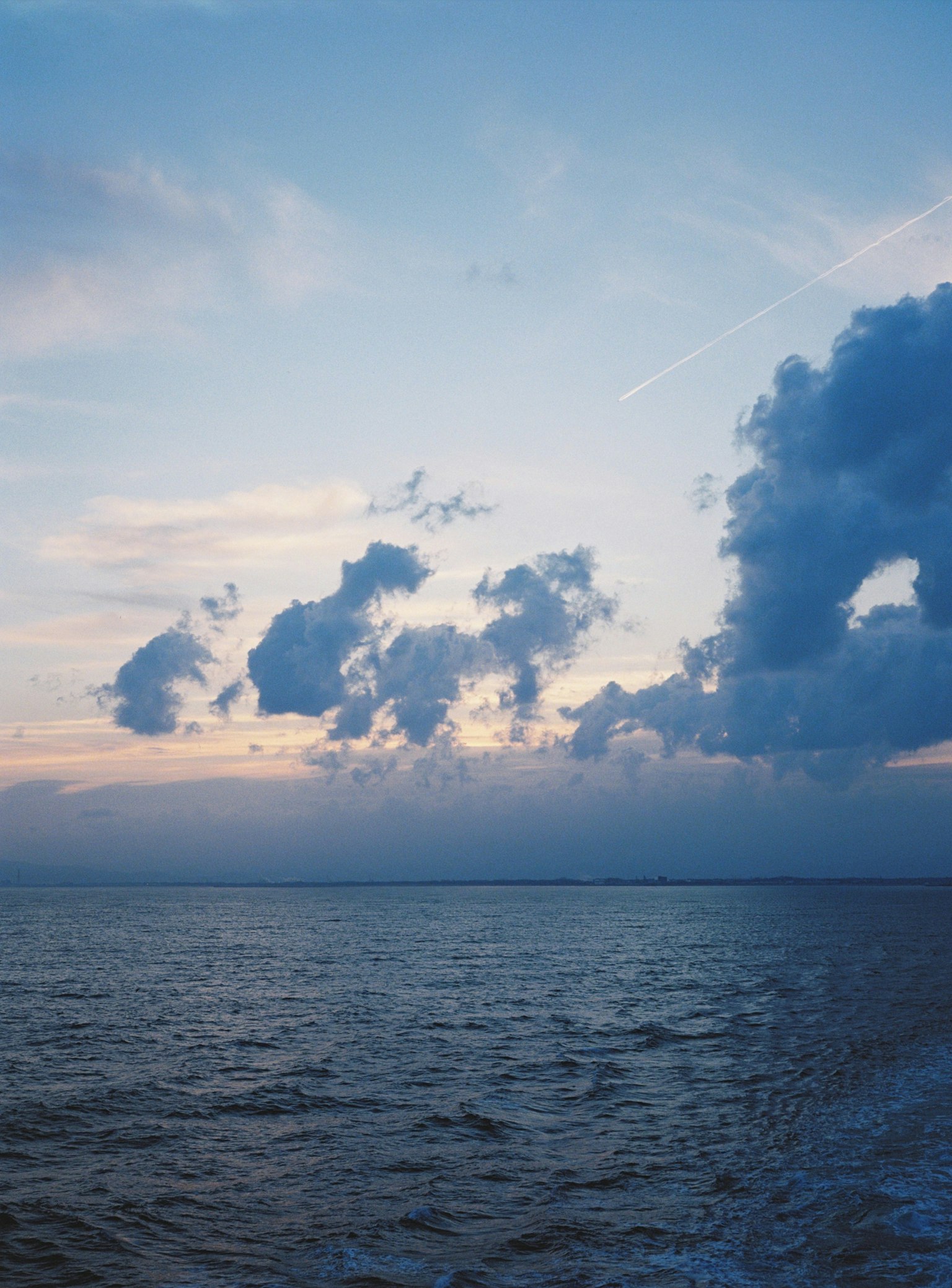Oceano blu con nuvole in un cielo al tramonto