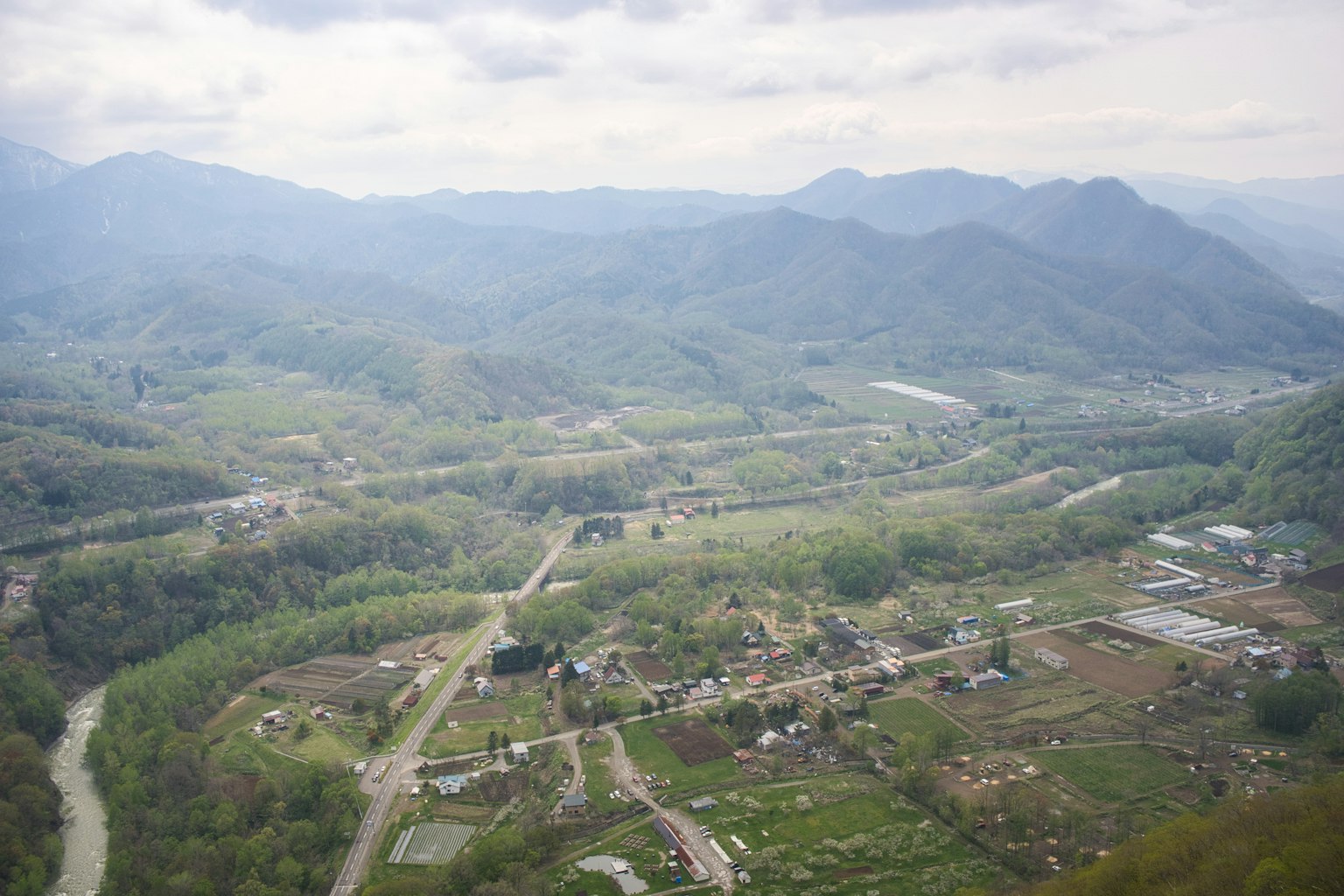 Landschaft mit grünem Tal und Dorf umgeben von Bergen
