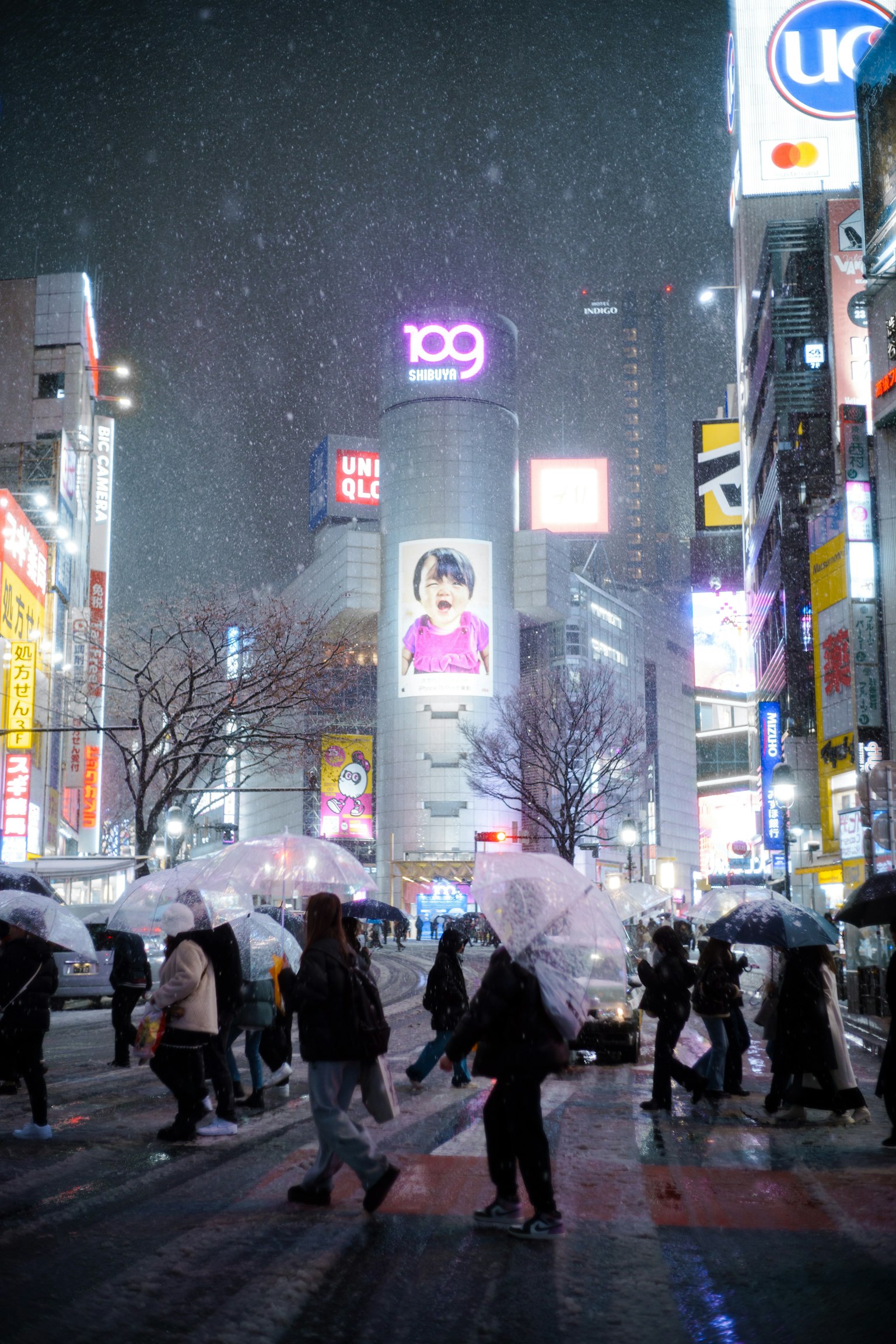 人們在雪夜裡帶著伞穿越澀谷十字路口