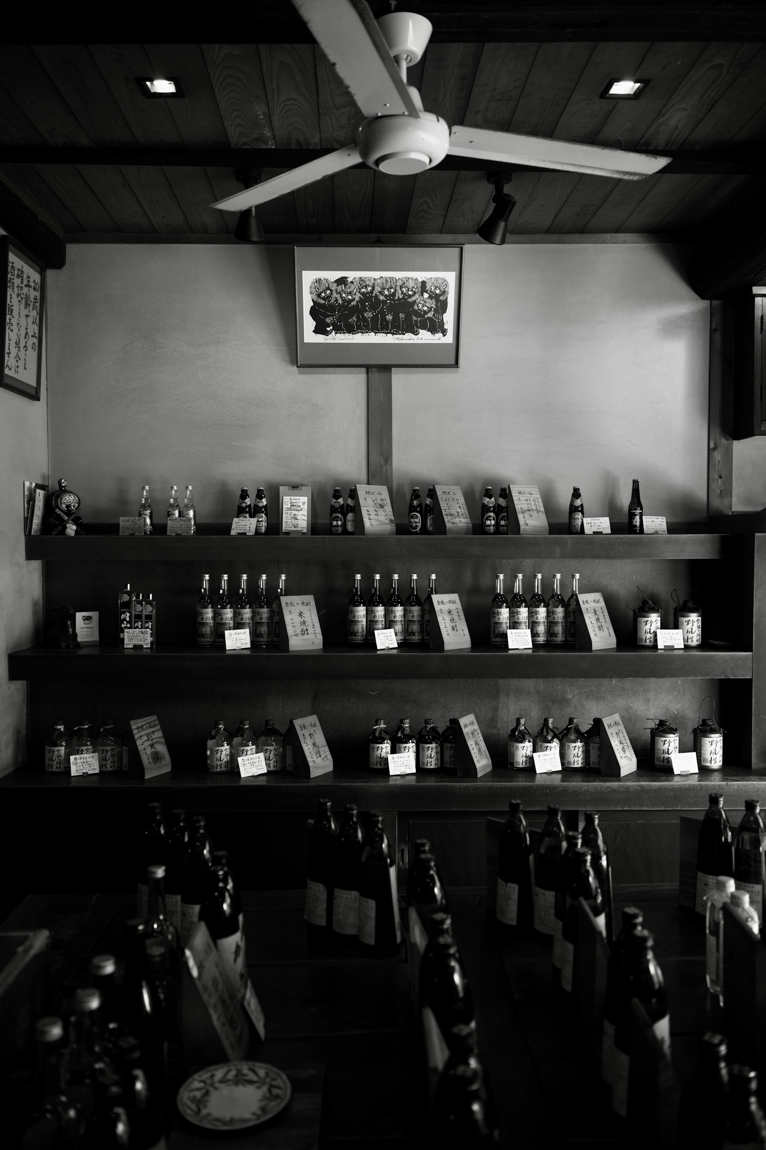 Interior en blanco y negro de una licorería con botellas organizadas en estantes