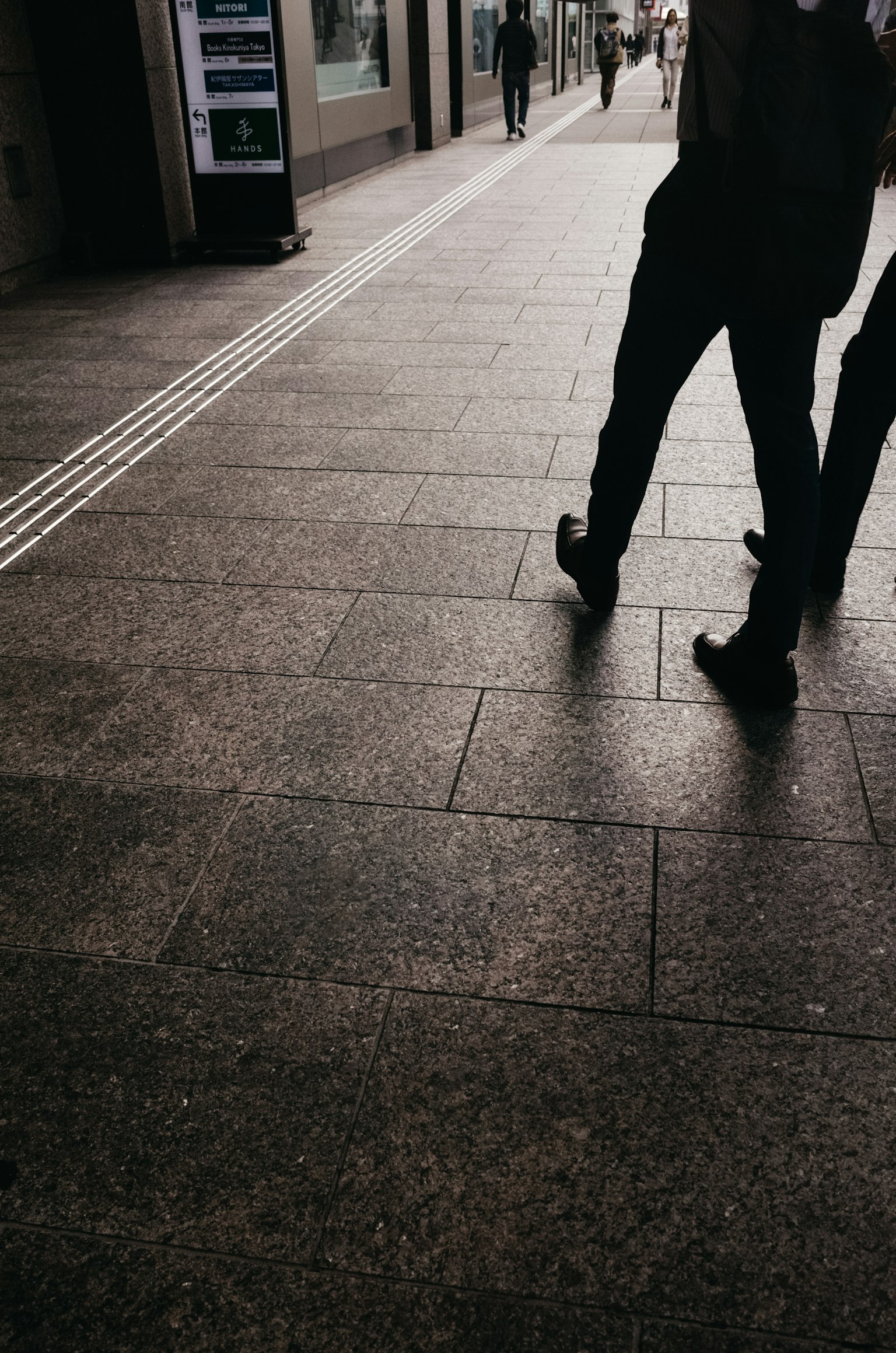 Silhouetten von Menschen, die auf einer gepflasterten Straße gehen