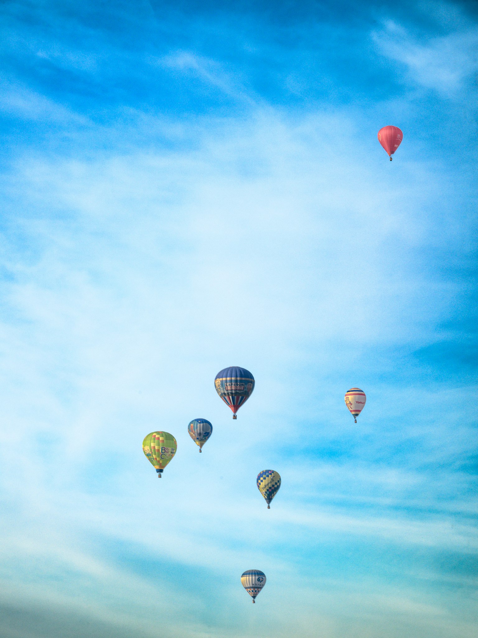 青空に浮かぶカラフルな熱気球の群れ
